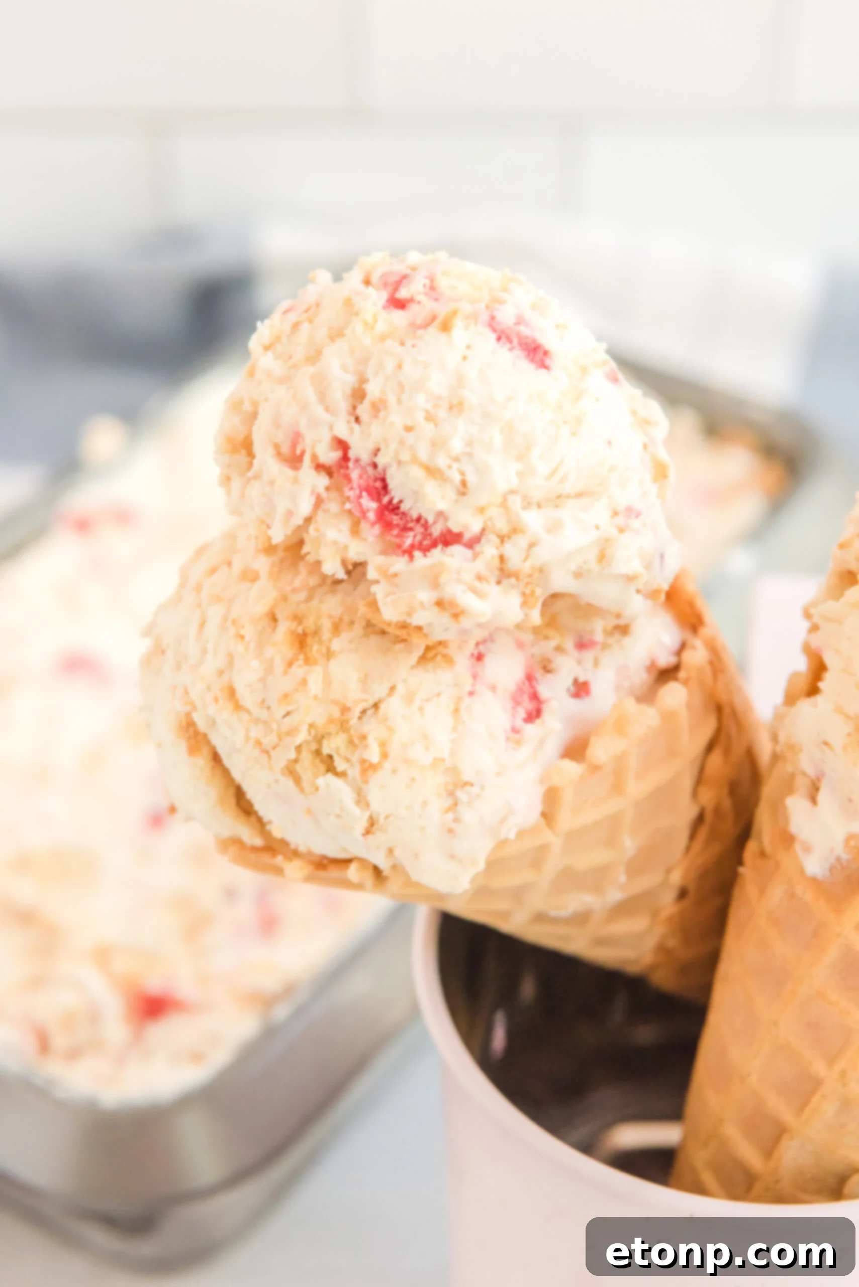 Up close view of a waffle cone with a scoop of Strawberry Cheesecake Ice Cream.