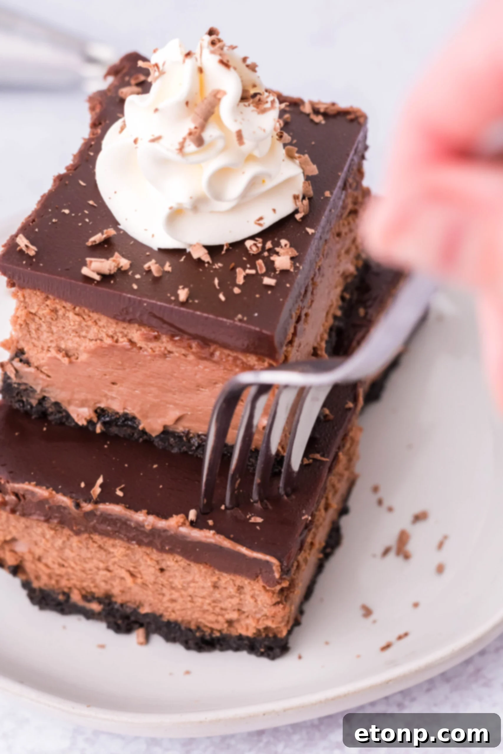 A fork removing a bite of chocolate cheesecake from one of the bars. 