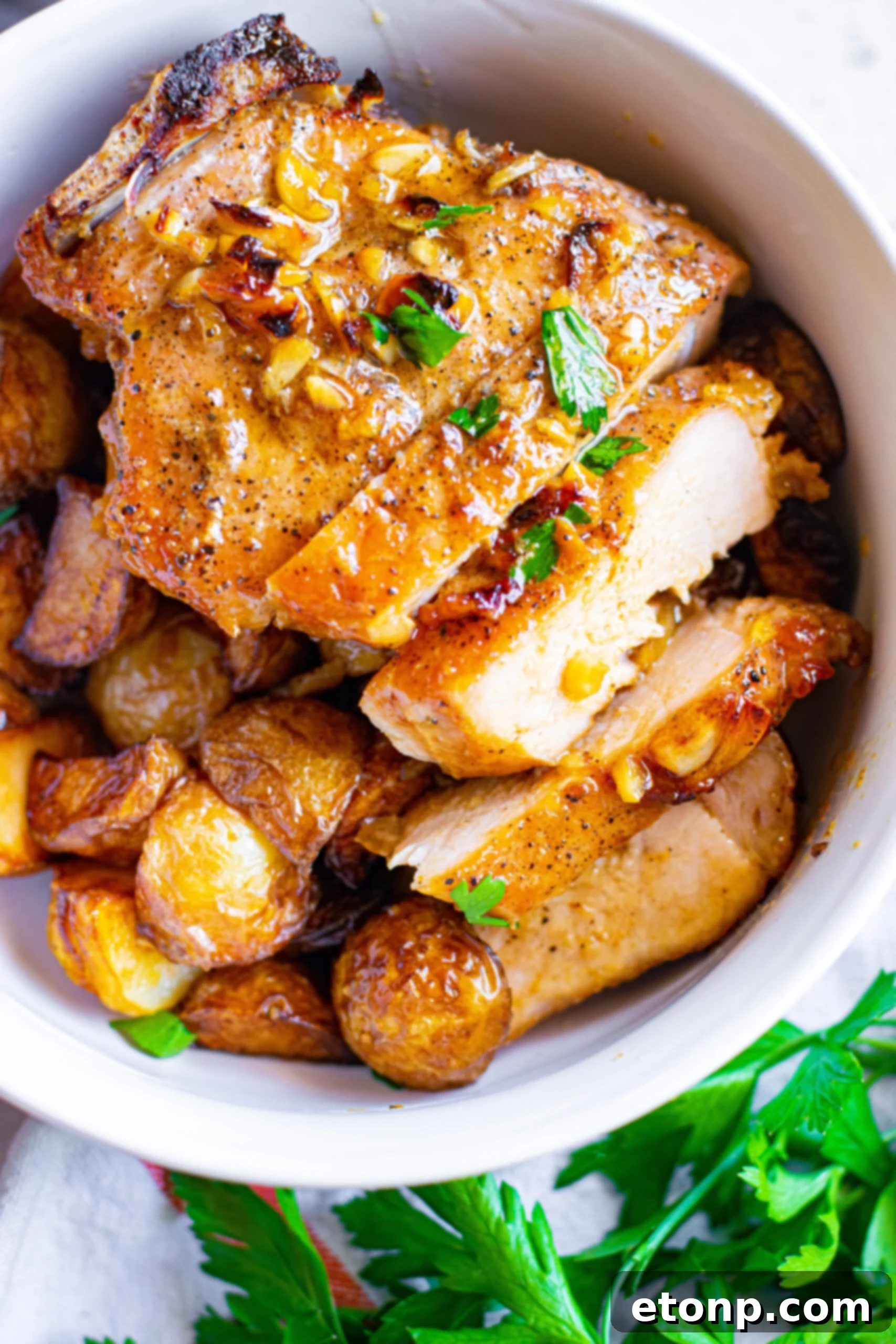 Close up view of Honey Garlic Pork Chops cut into strips and served over potatoes, emphasizing the juicy interior.