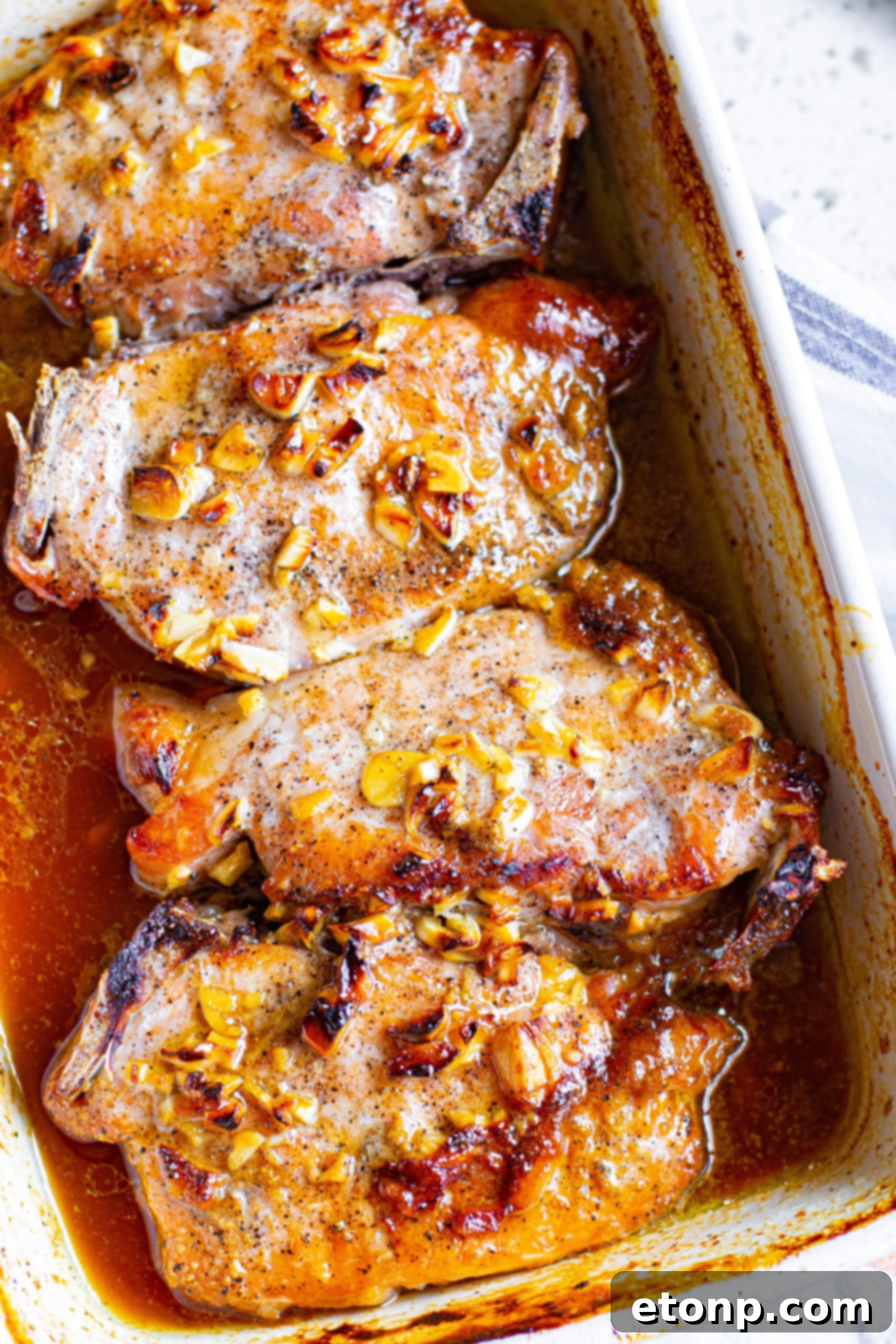 Close up view of Honey Garlic Pork Chops in a white baking dish, showcasing the rich glaze.