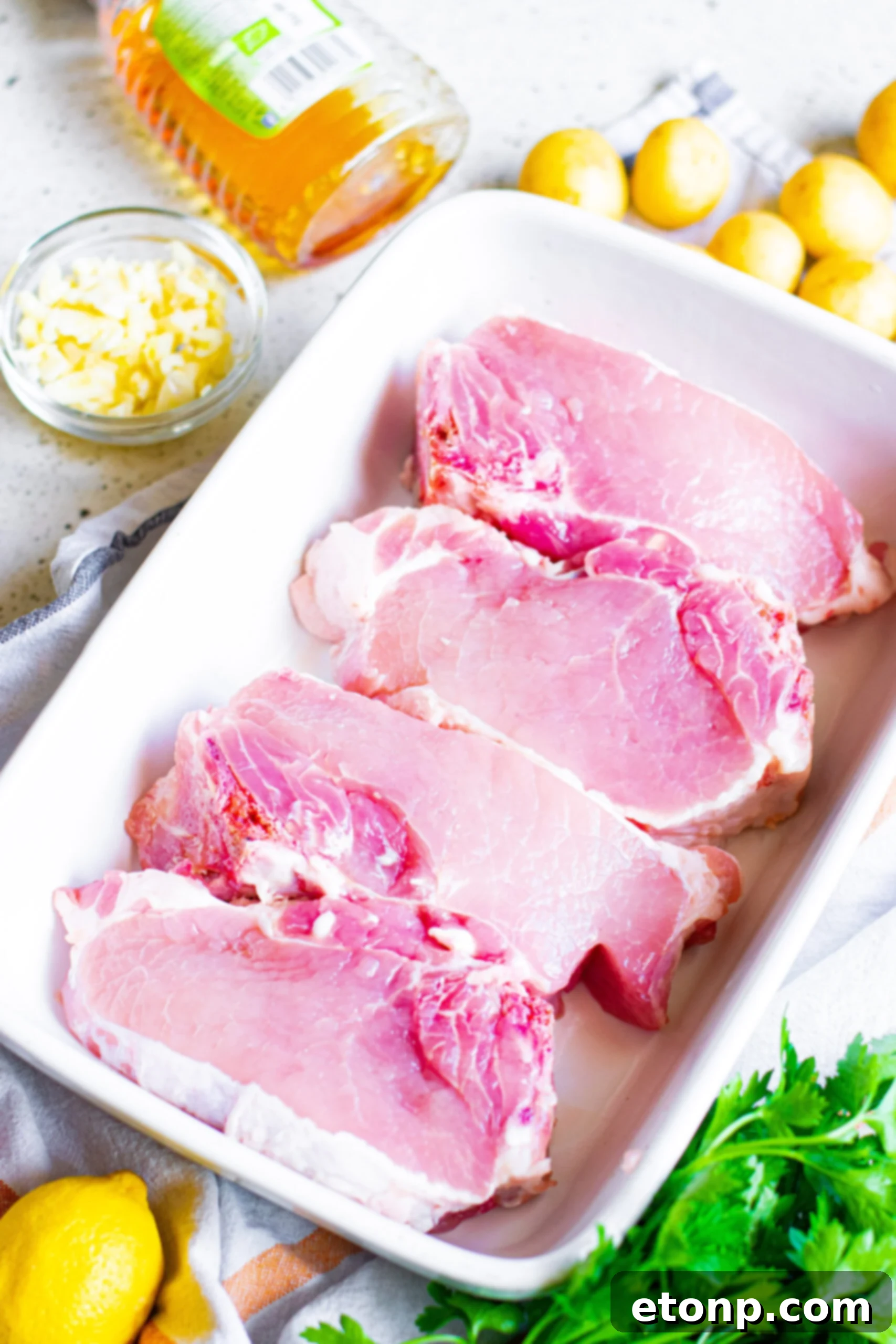 Overhead view of the ingredients needed to complete this recipe, including pork chops, honey, garlic, and lemon.