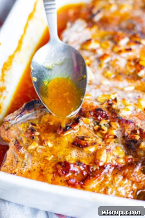 Pork chops covered with foil, marinating in the baking dish.