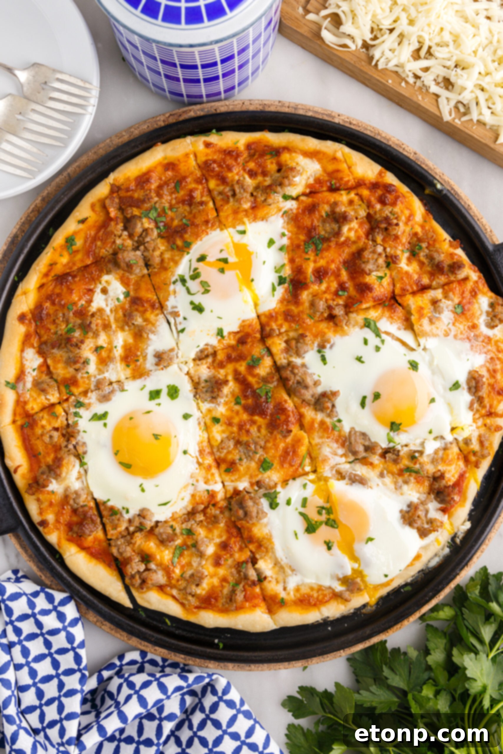Overhead view of Breakfast Pizza on a black pizza dish cut into square slices.