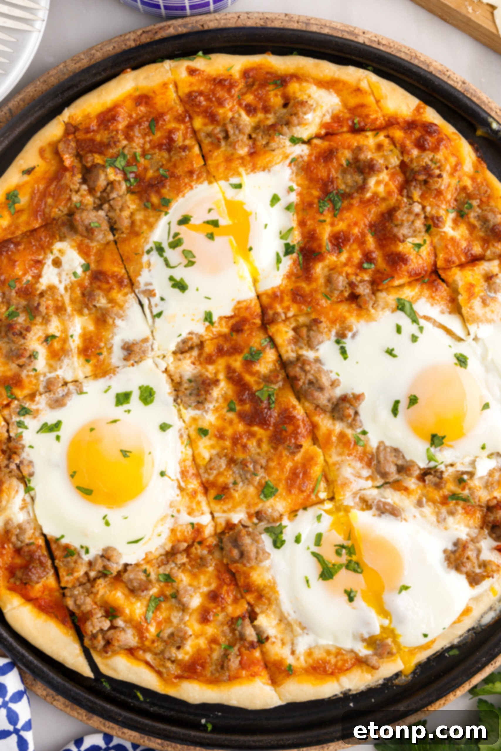 Overhead view of Breakfast Pizza on a black pizza dish cut into square slices.