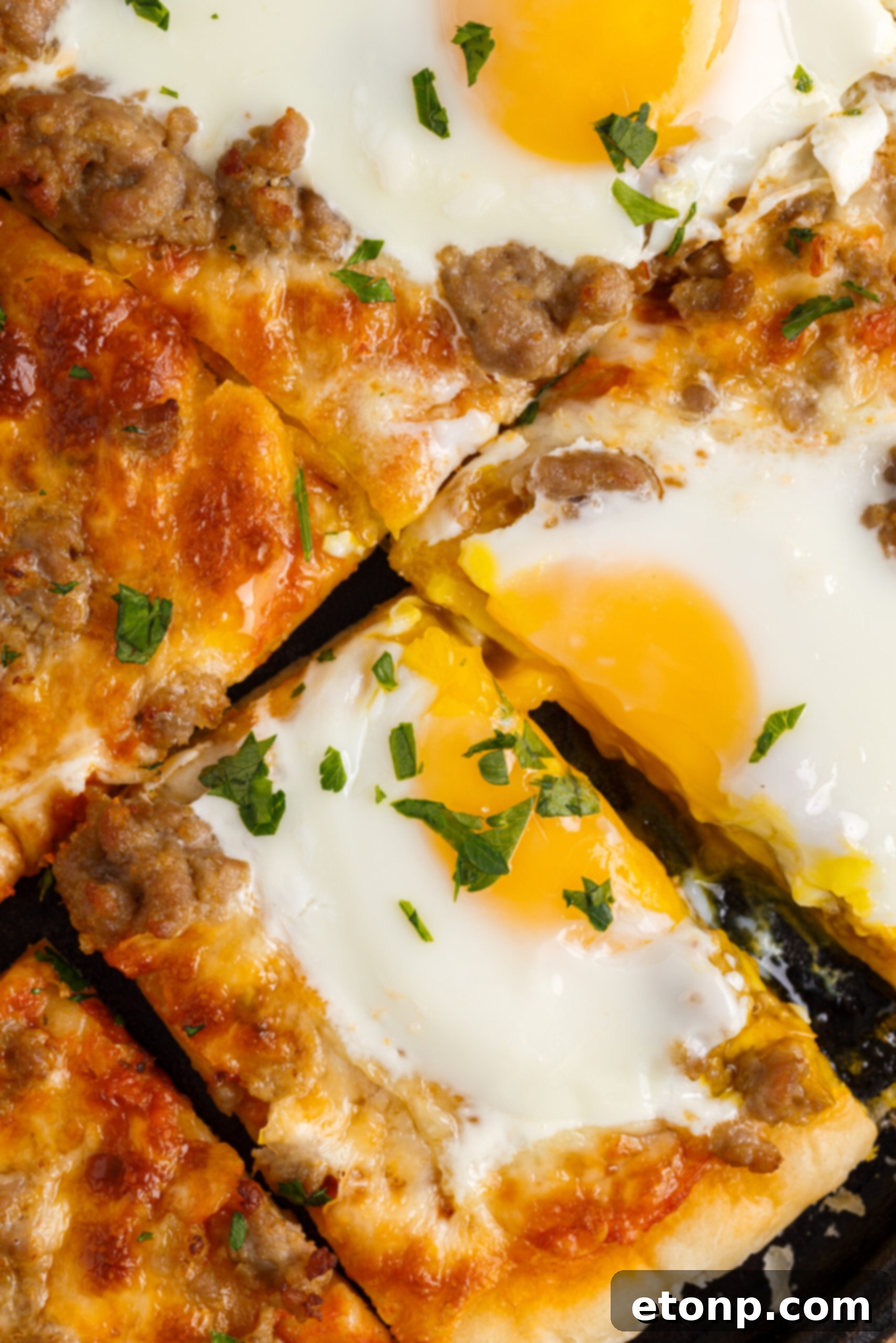 Close up view of Breakfast Pizza on a black pizza dish cut into square slices.