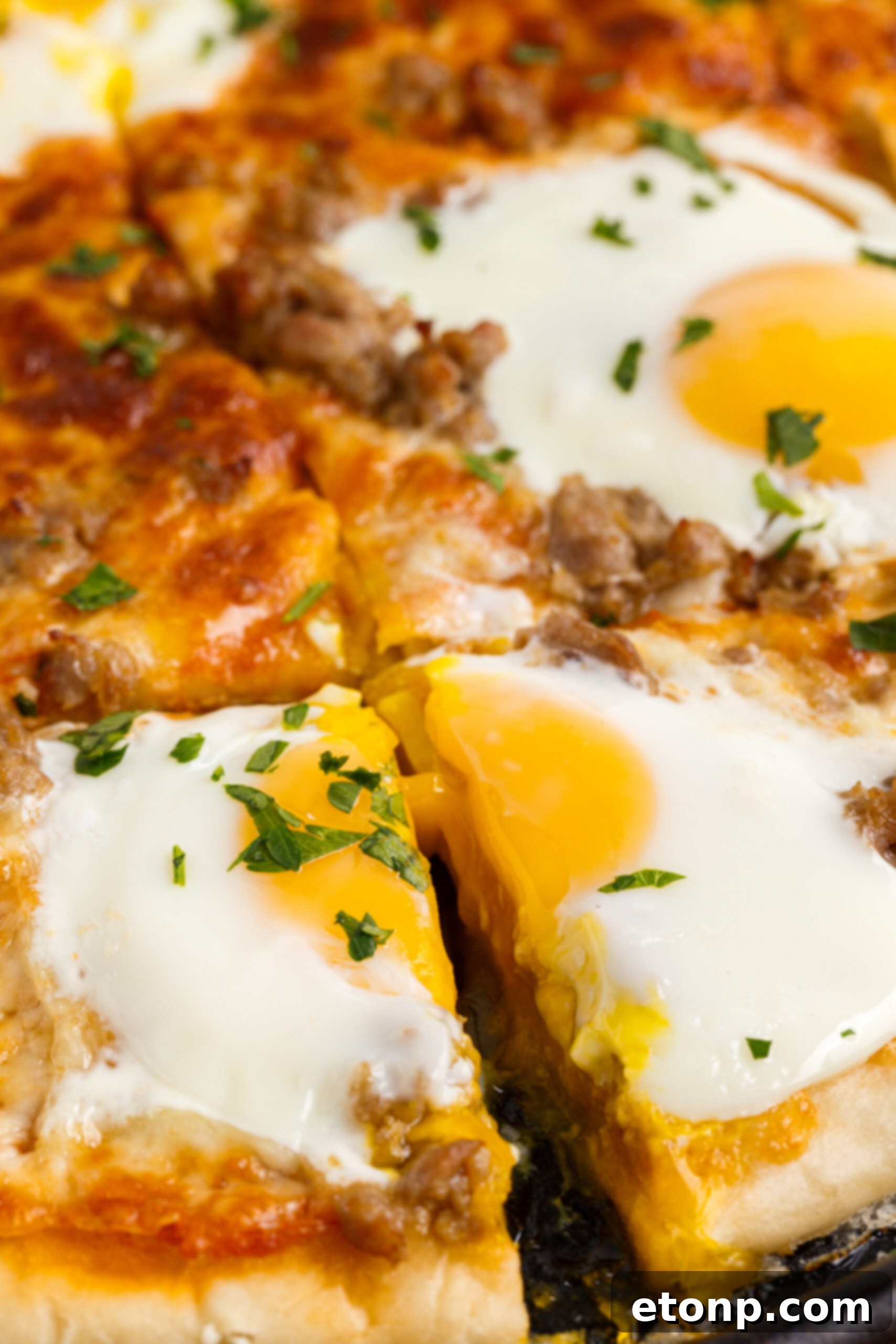 Close up view of Breakfast Pizza on a black pizza dish cut into square slices.