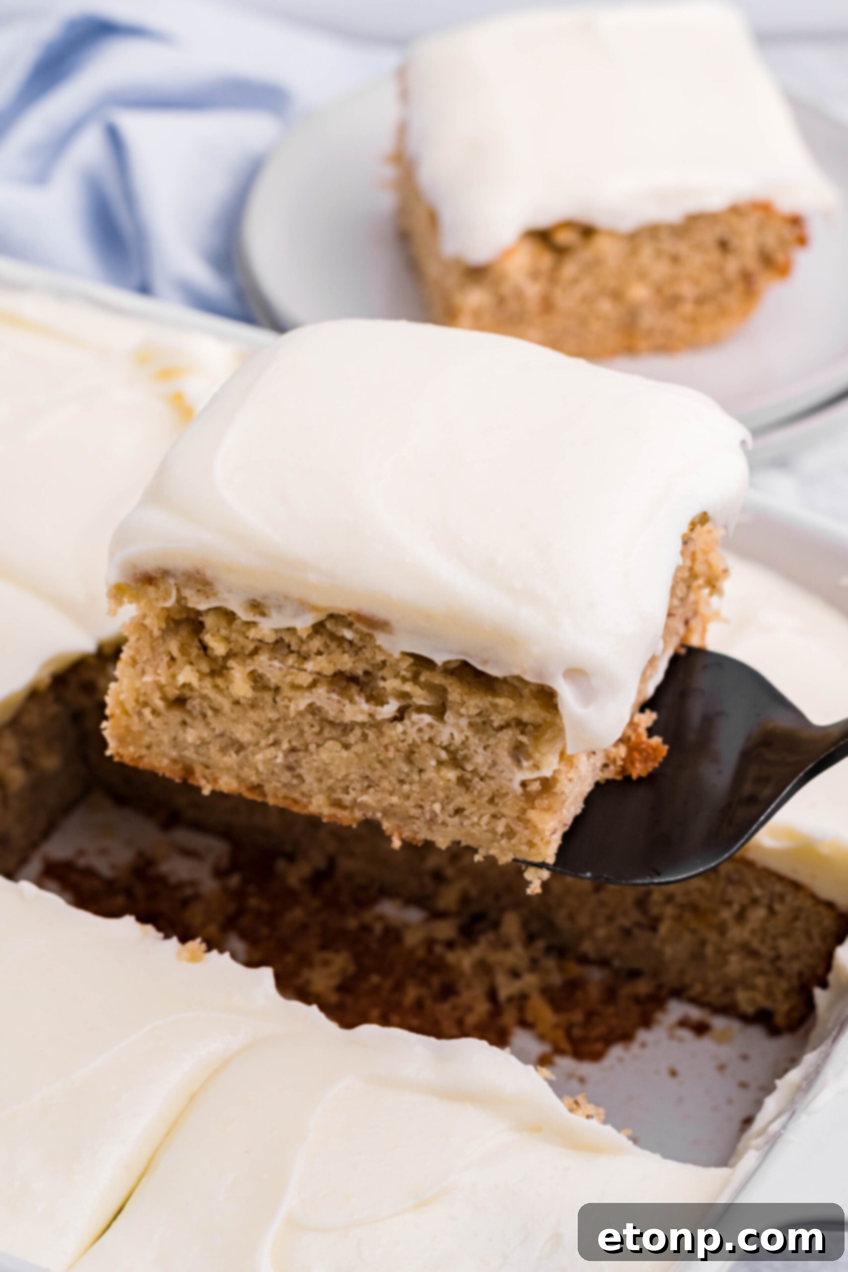 Side view of a slice of Banana Sheet Cake on a black cake server.