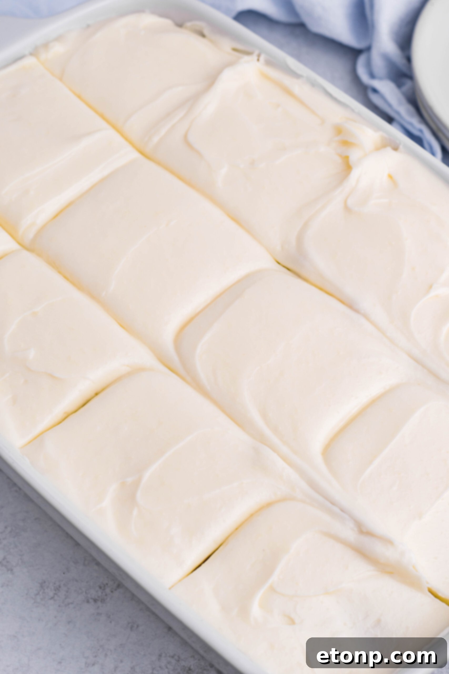 Close up view of Banana Sheet Cake in a white baking dish cut into slices.