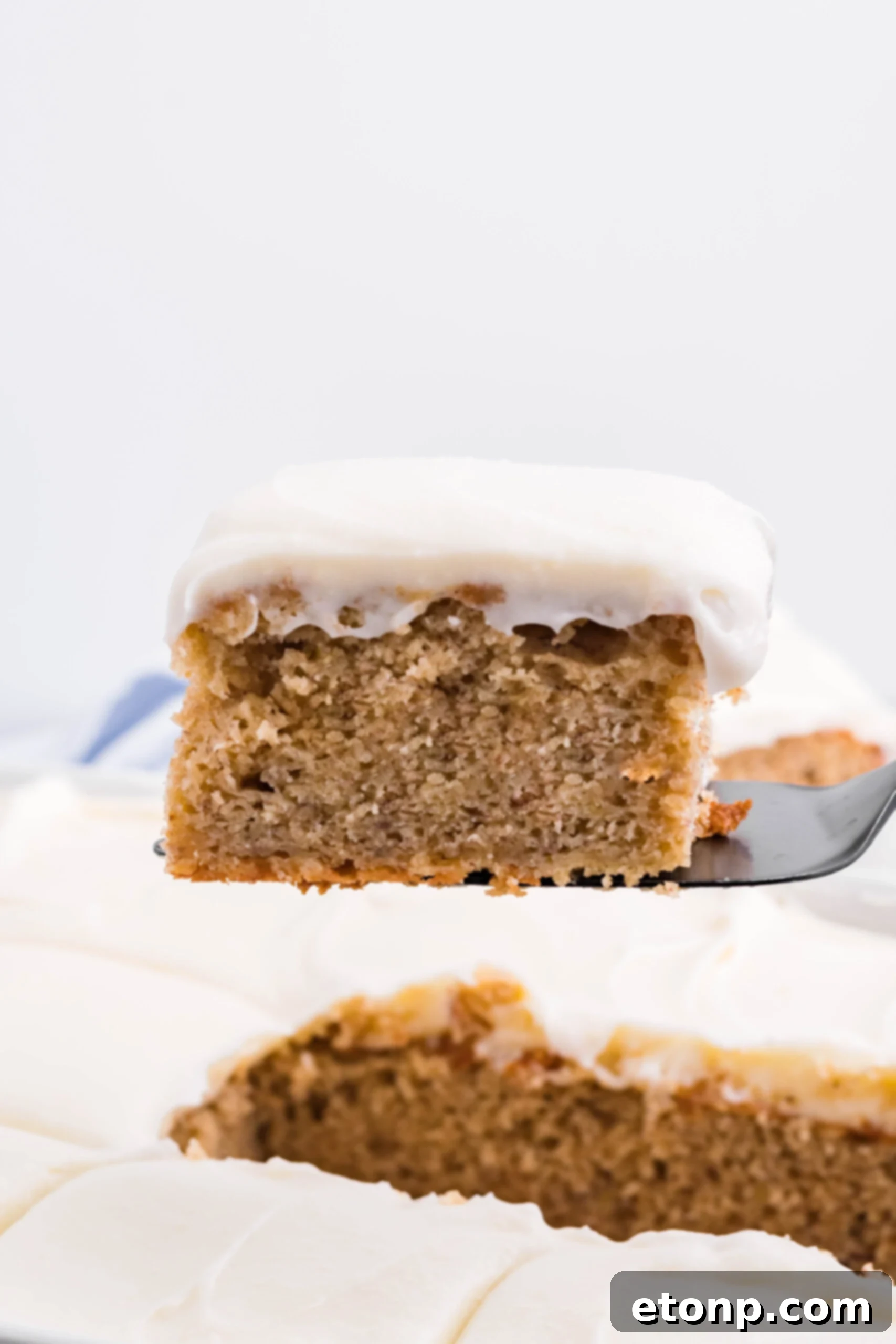 Side view of a slice of Banana Sheet Cake on a black cake server.