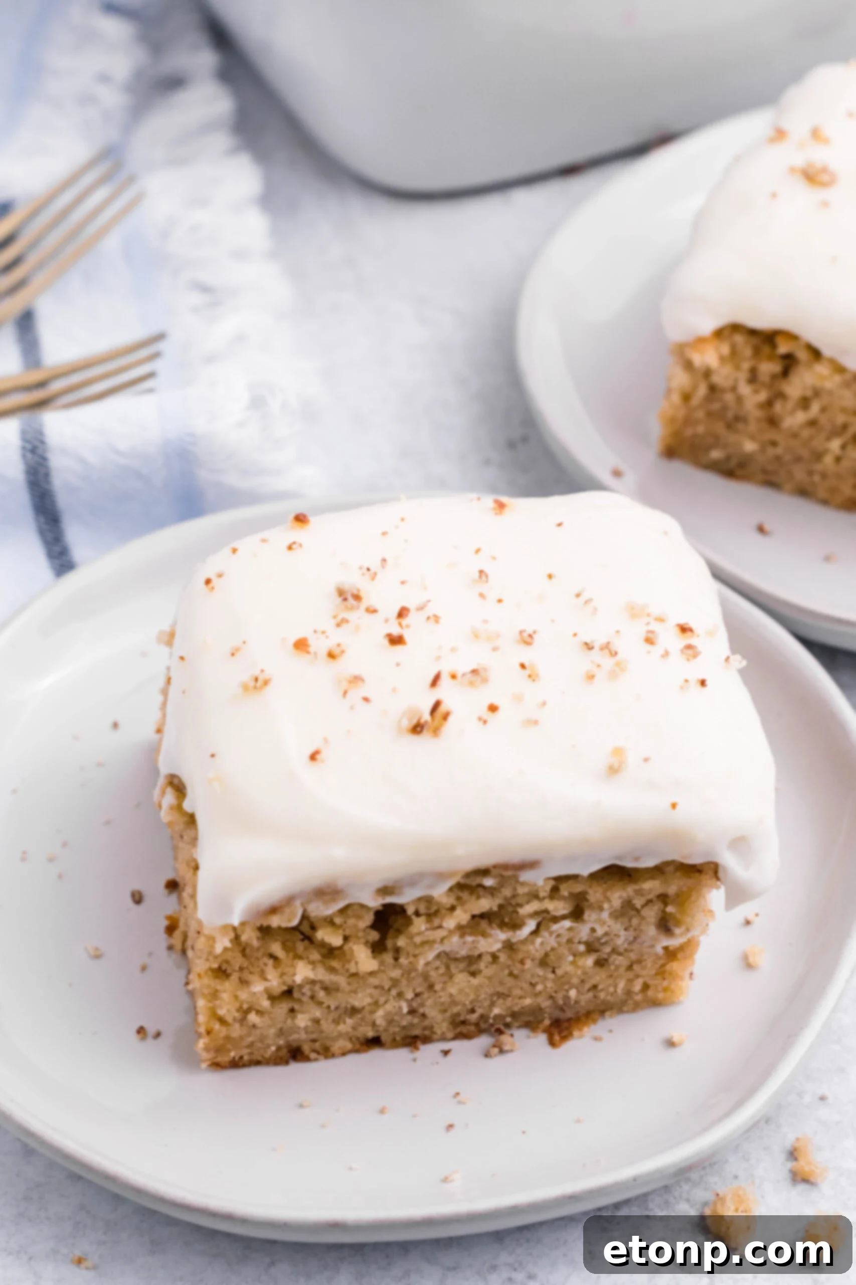 Close up view of a slice of Banana Sheet Cake on a white plate.