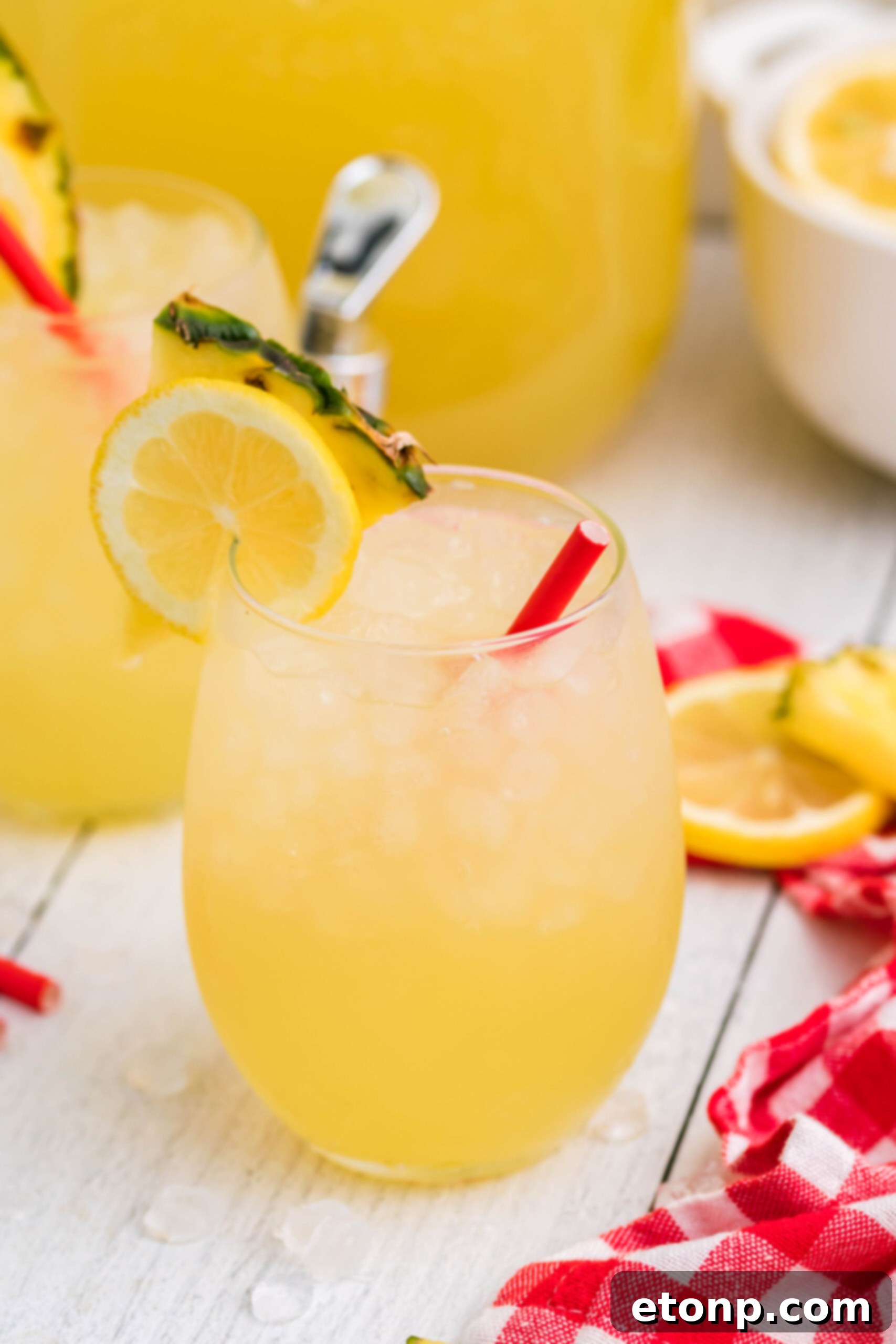 Front view of two glasses of Pineapple Vodka Lemonade garnished with a lemon and pineapple slice, ready to be enjoyed.