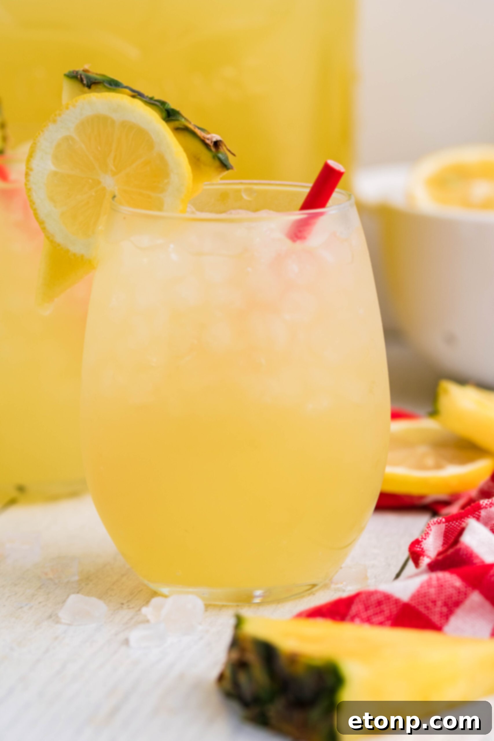 Front view of two glasses of Pineapple Vodka Lemonade garnished with a lemon and pineapple slice, ready for a toast.