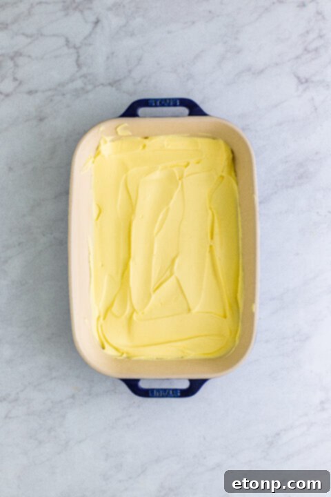 Fresh banana slices meticulously arranged over a layer of pudding, preparing for the next layer of graham crackers.