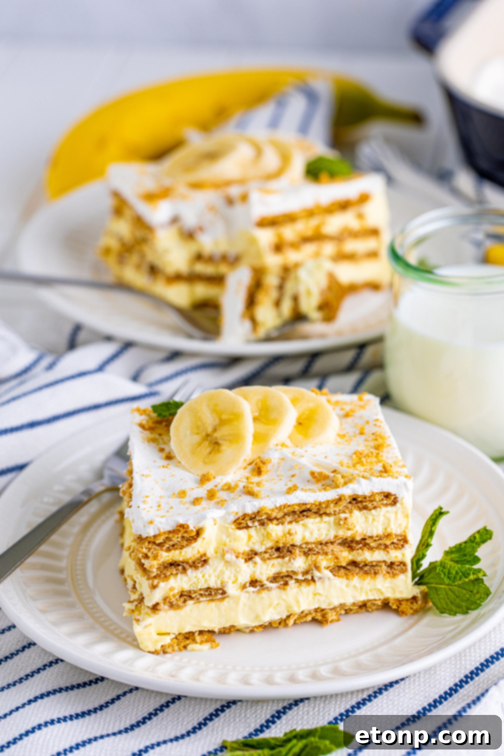 A pristine slice of Banana Icebox Cake sits elegantly on a white plate, ready to be enjoyed.