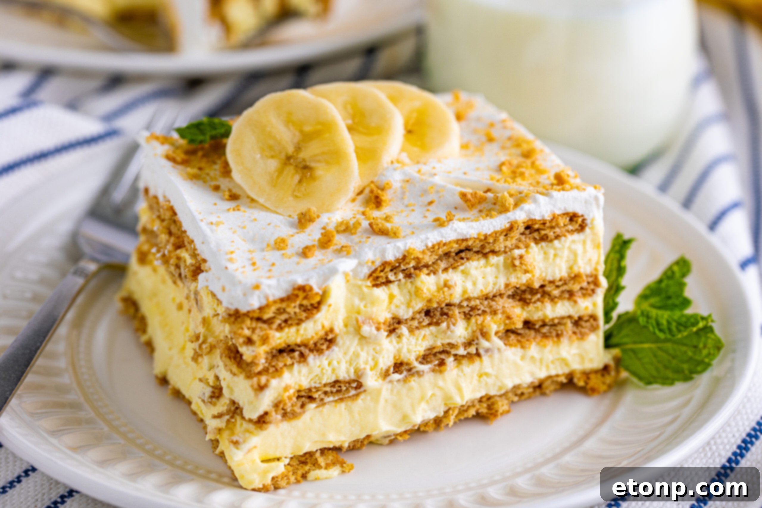 A wide overhead shot of the No-Bake Banana Icebox Cake in a blue baking dish, adorned with artfully arranged fresh banana slices on top.