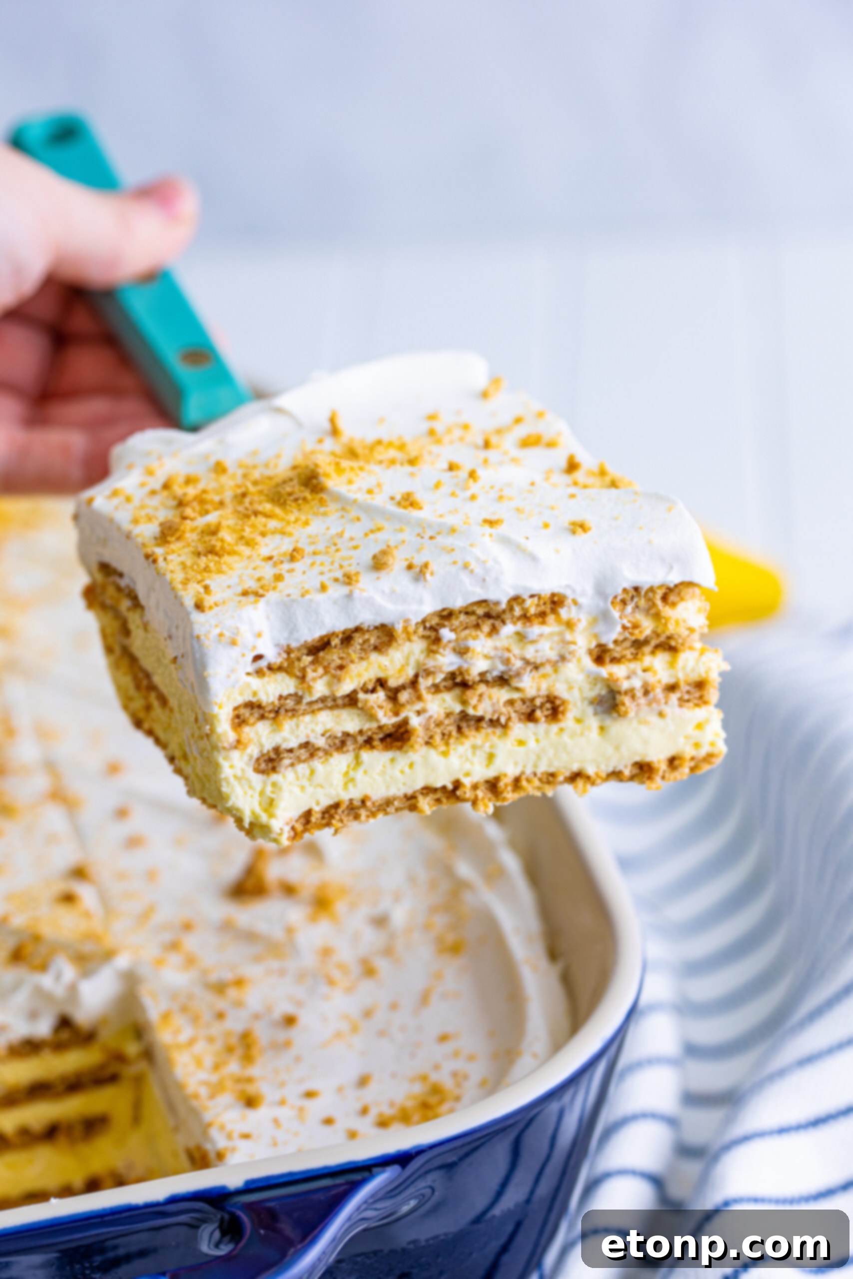 A serving spatula lifting a single, elegant slice of Banana Icebox Cake, showcasing its beautiful layers before being placed on a plate.