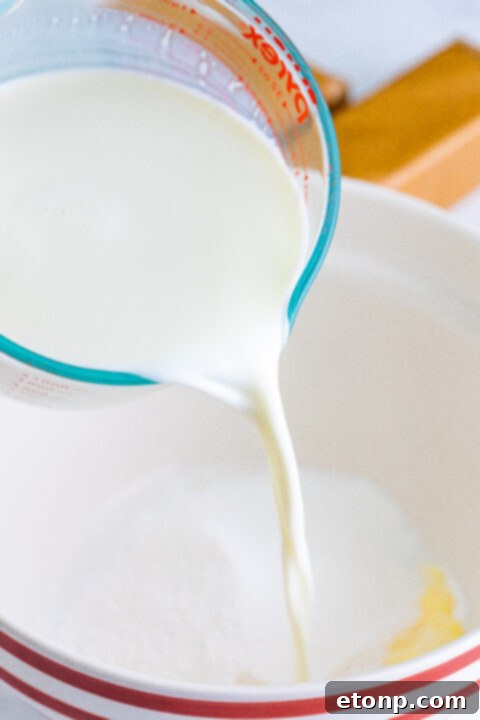 Close-up of a bowl filled with banana cream pudding mix and cold milk, being whisked to combine.