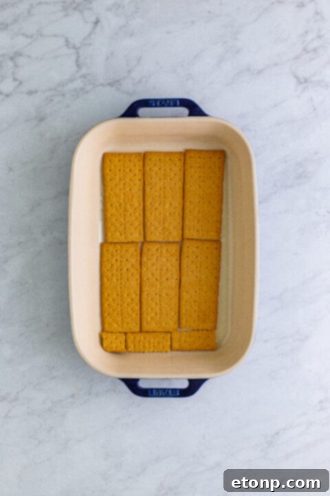 A layer of creamy banana pudding mixture spread evenly over the graham crackers in the baking dish.