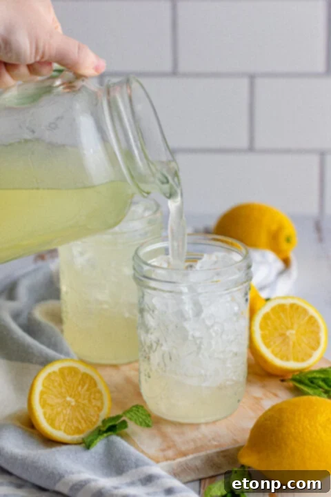 Finished homemade lemonade being poured into a serving pitcher.