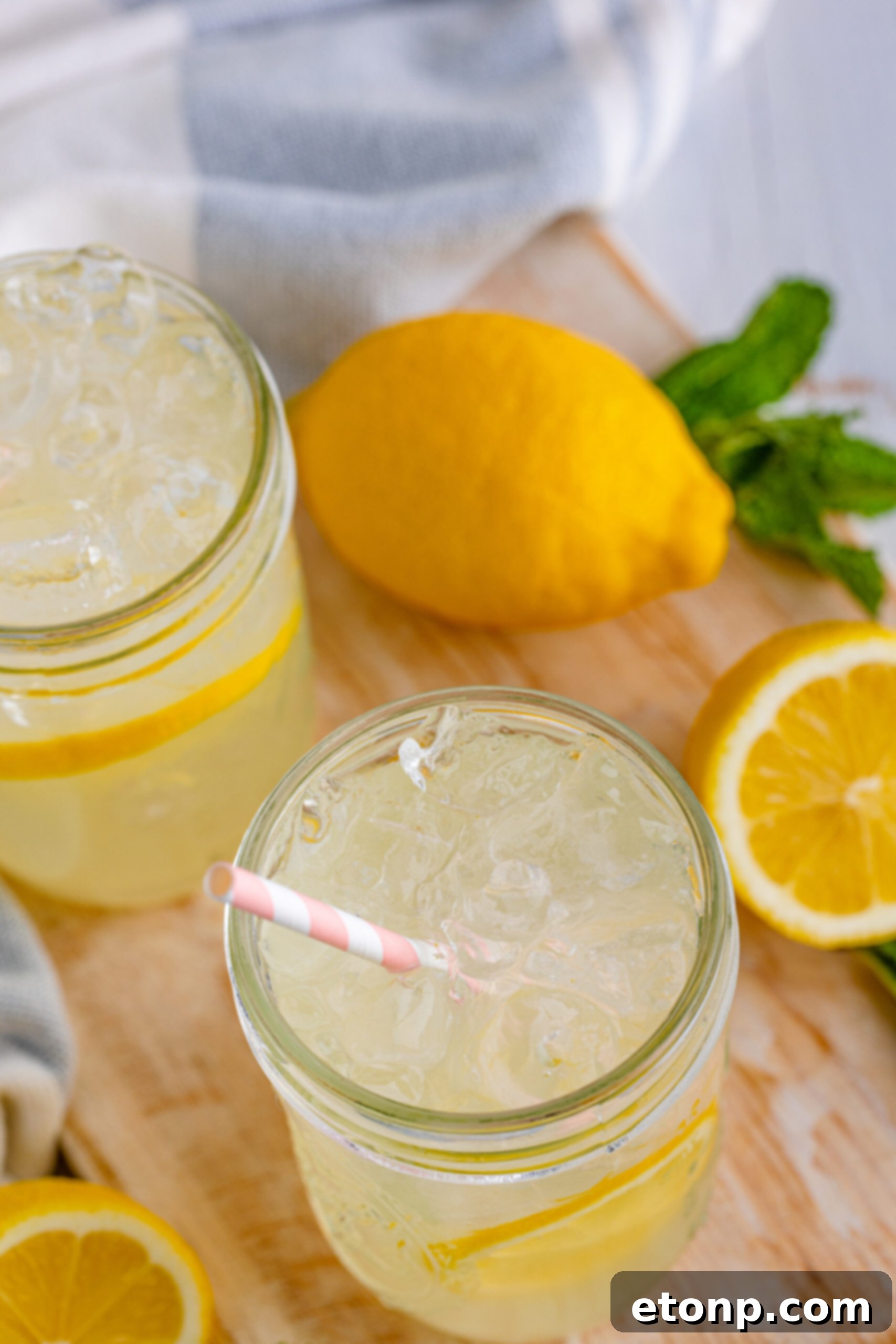 Overhead shot of two mason jars of homemade lemonade on a bright wooden surface.