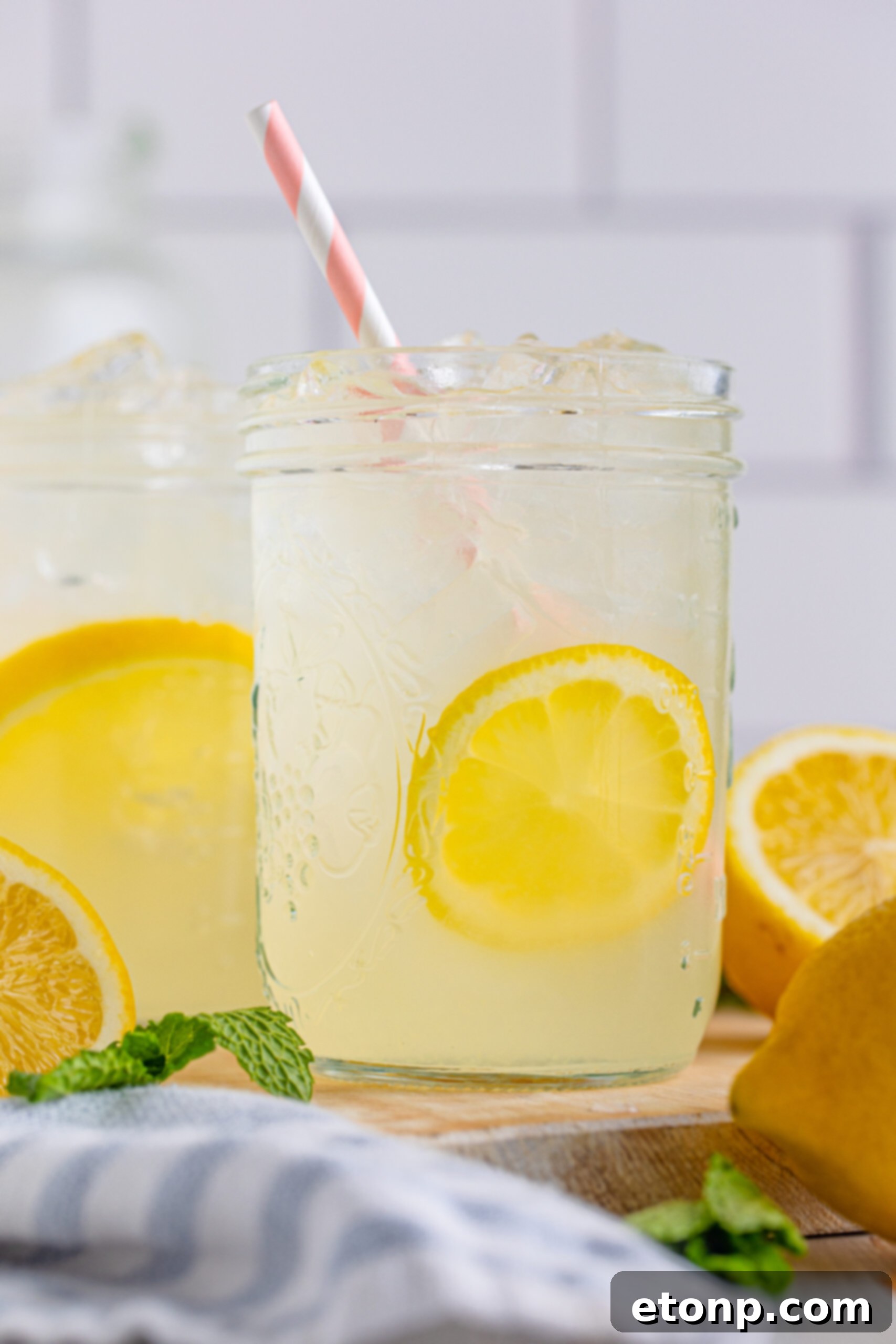 Close-up view of two mason jars of homemade lemonade, with a focus on the refreshing beverage and lemon garnishes.
