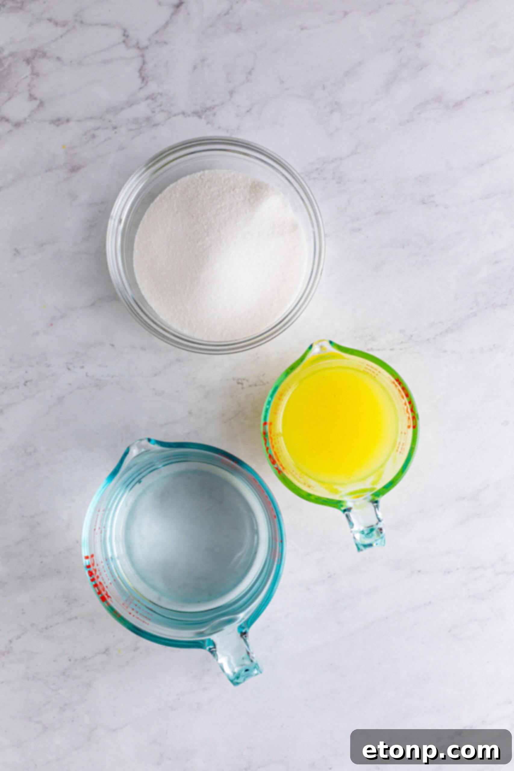 An overhead view of lemons, sugar, and water, the three core ingredients for making homemade lemonade, neatly arranged.