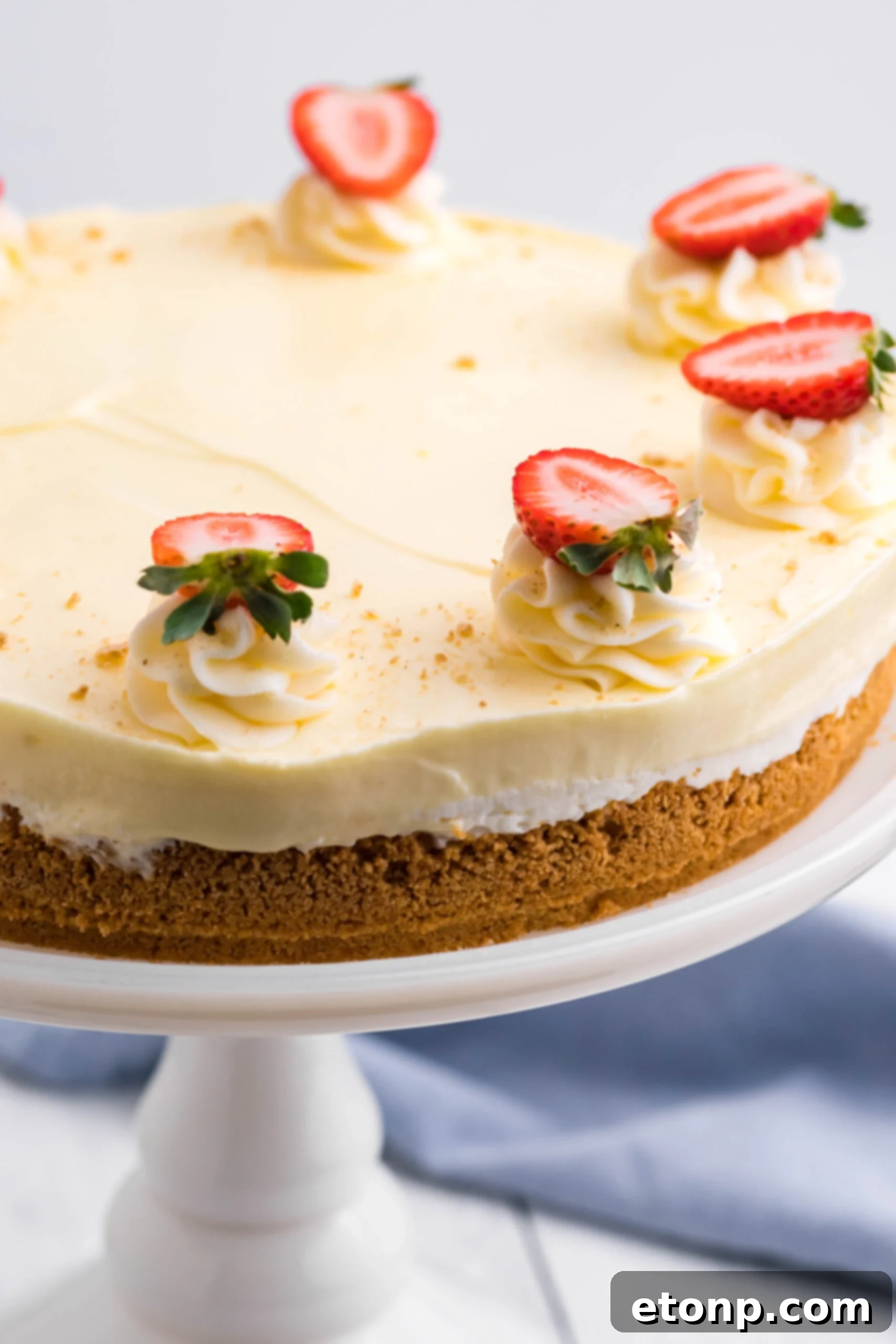 Close up view of Banana Cream Cheesecake on a white cake stand, showcasing its creamy layers and fresh banana slices.