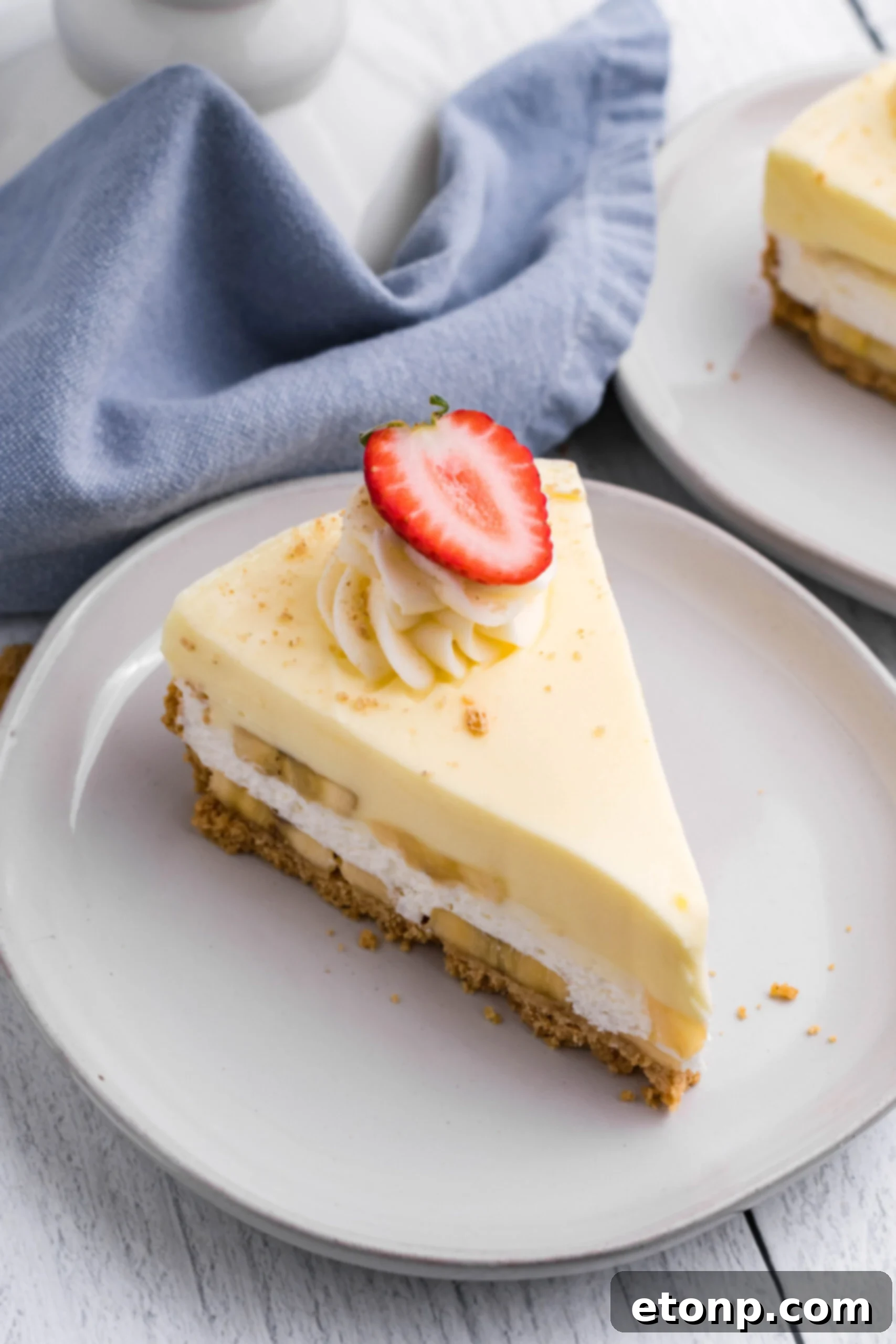 Close up view of a slice of Banana Cream Cheesecake on a white plate, ready to be enjoyed.