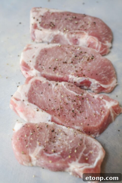 A close-up of a perfectly seared pork chop being placed into a skillet with rich caramelized onion gravy.