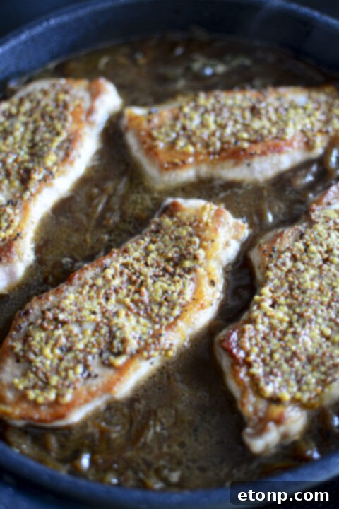 Melted provolone cheese gently placed atop a French Onion Pork Chop in the skillet.