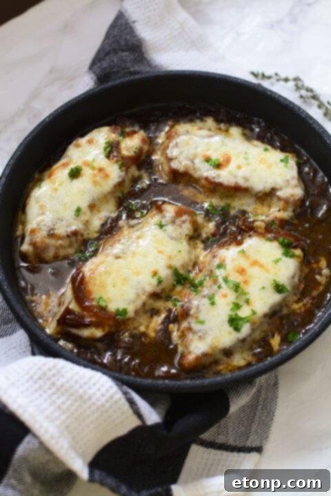Final stage of French Onion Pork Chops in the skillet, with cheese perfectly melted and bubbly.