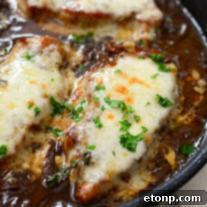 French Onion Pork Chops in a cast iron skillet with mashed potatoes.