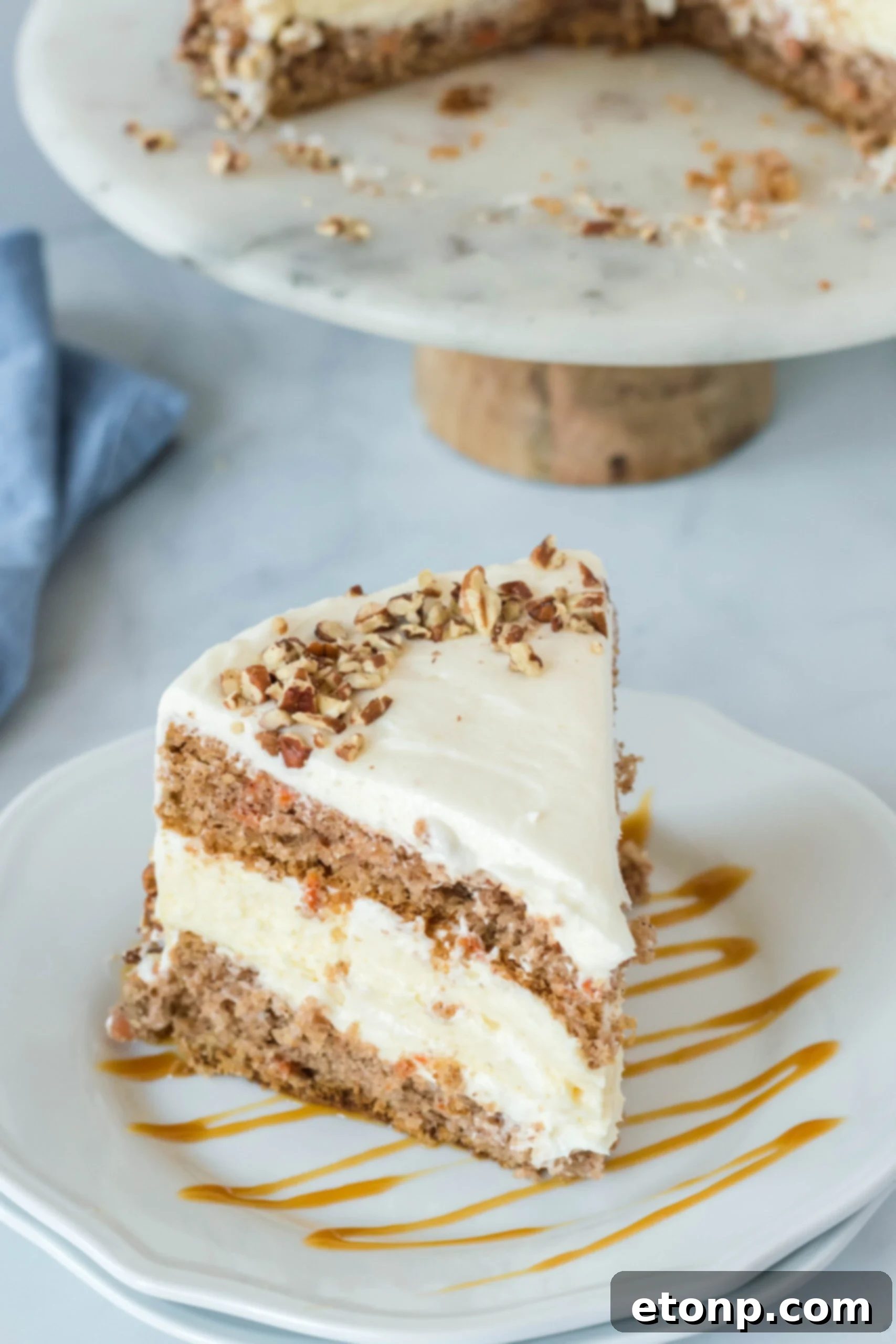 Front view of a slice of Carrot Cake Cheesecake on a white plate drizzled with caramel.