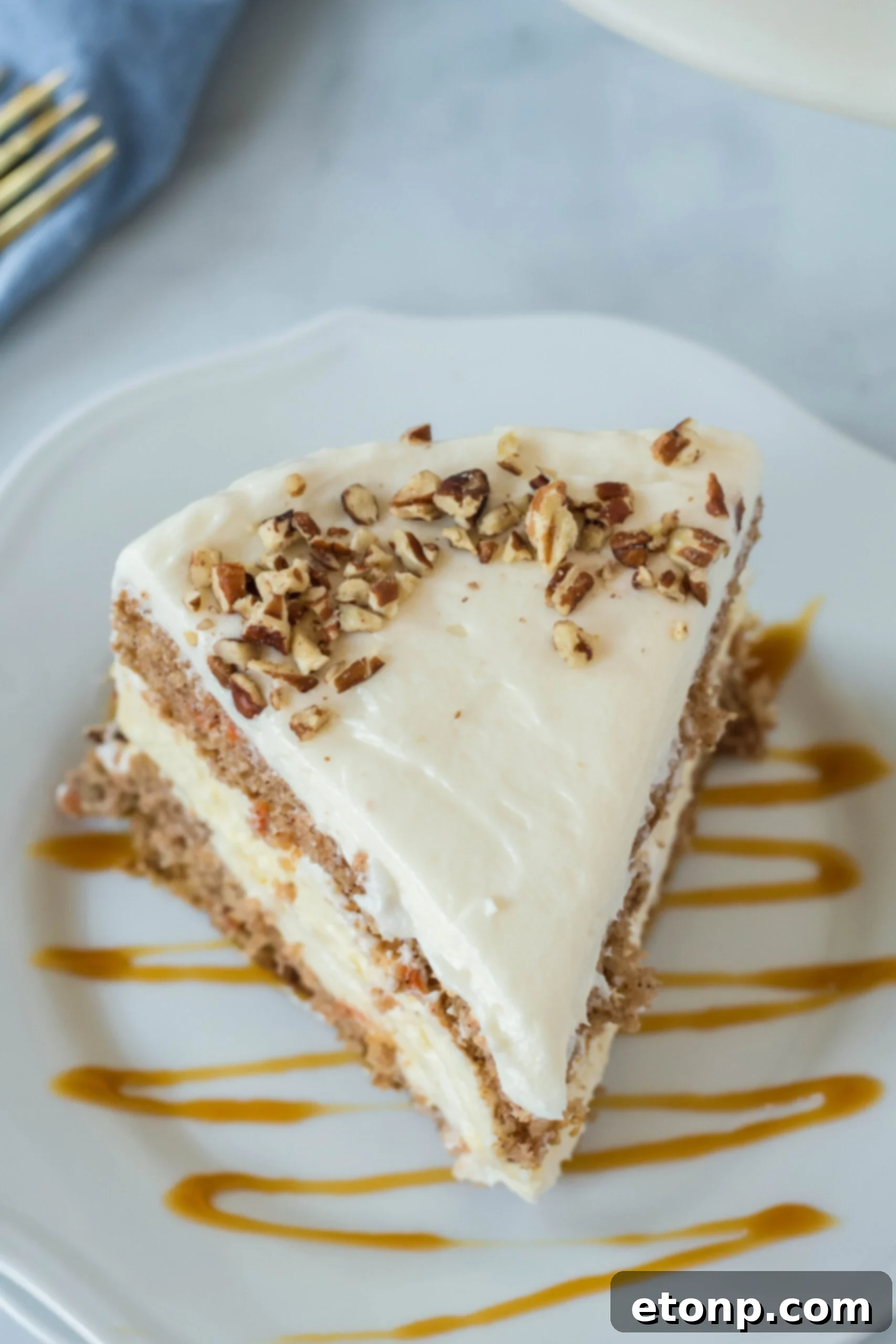 Overhead view of a slice of Carrot Cake Cheesecake on a white plate drizzled with caramel.