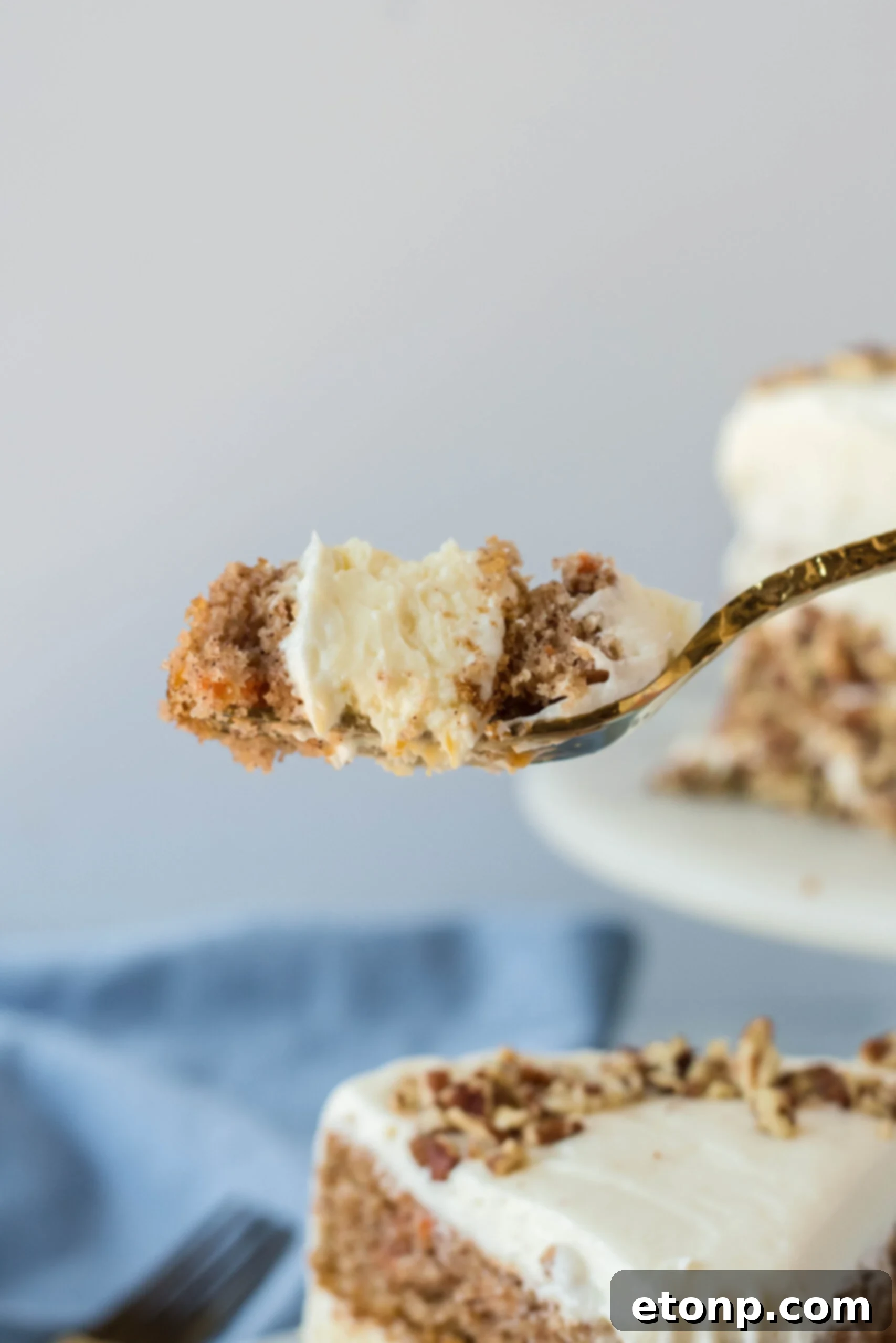 Side view of a bite of Carrot Cake Cheesecake on a gold fork.