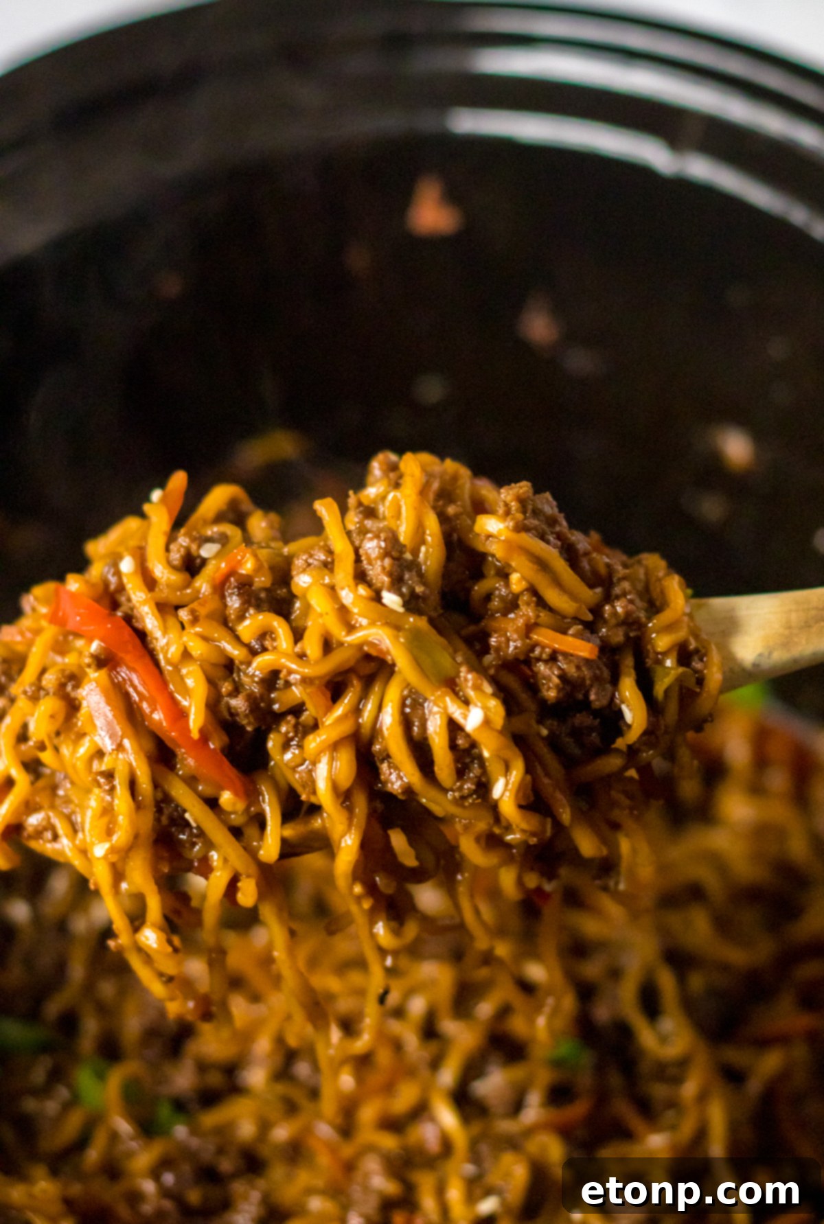 Hearty Slow Cooked Beef Ramen 6 Close up view of Slow Cooker Beef Ramen in a crock pot with a wooden spoon removing a serving.