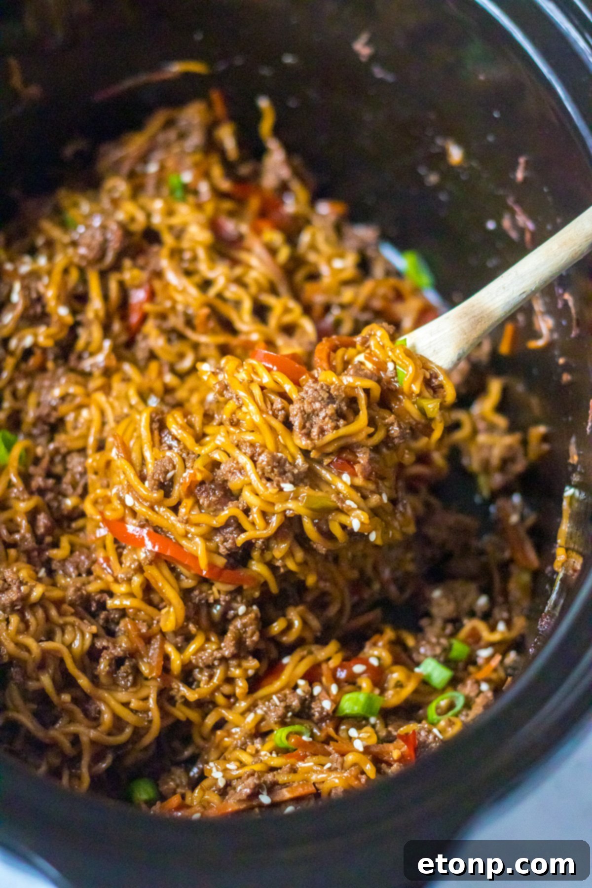 Hearty Slow Cooked Beef Ramen 7 View of Slow Cooker Beef Ramen in a crock pot with a wooden spoon removing a serving.