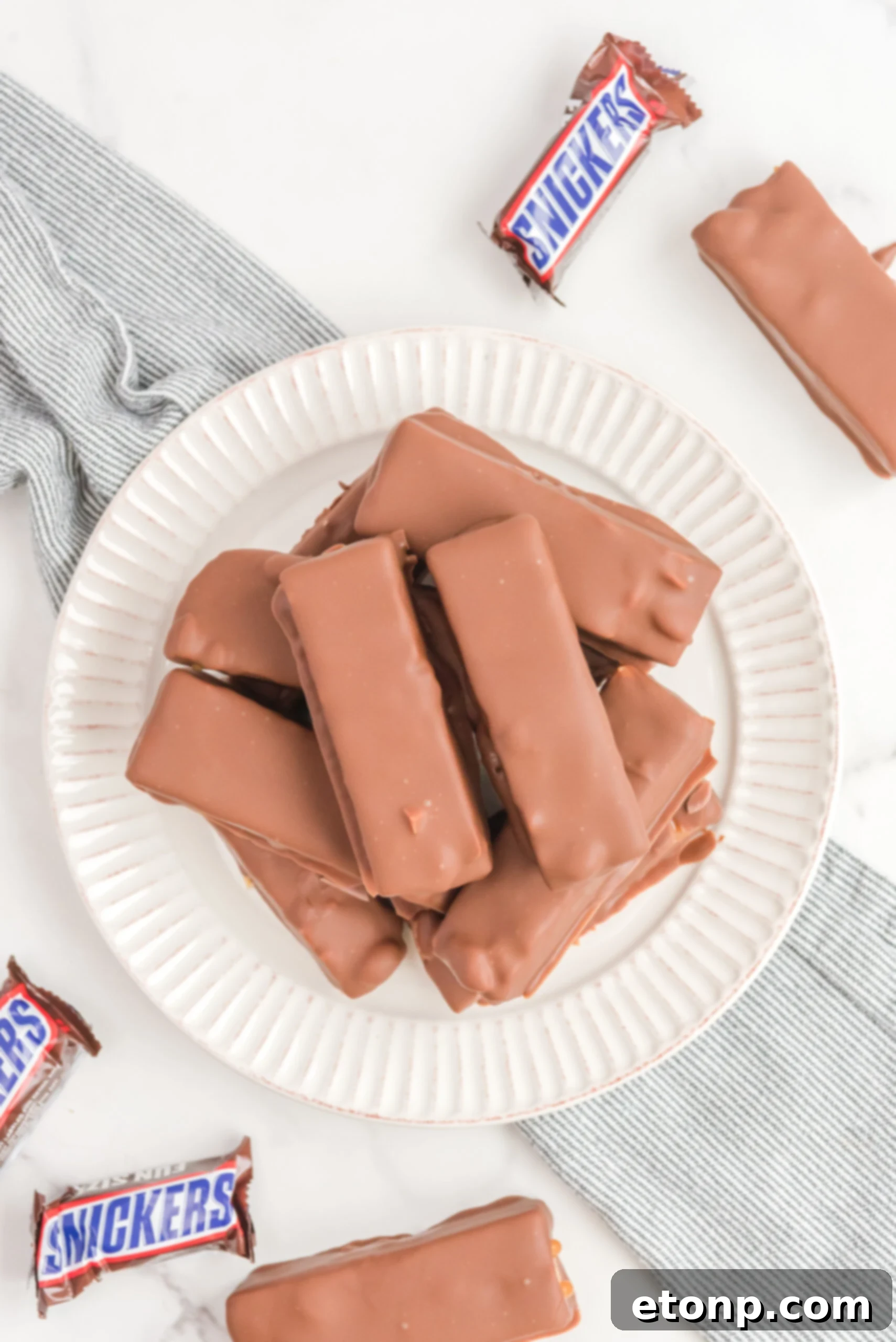 Overhead view of Homemade Snickers Bars stacked on a white plate.