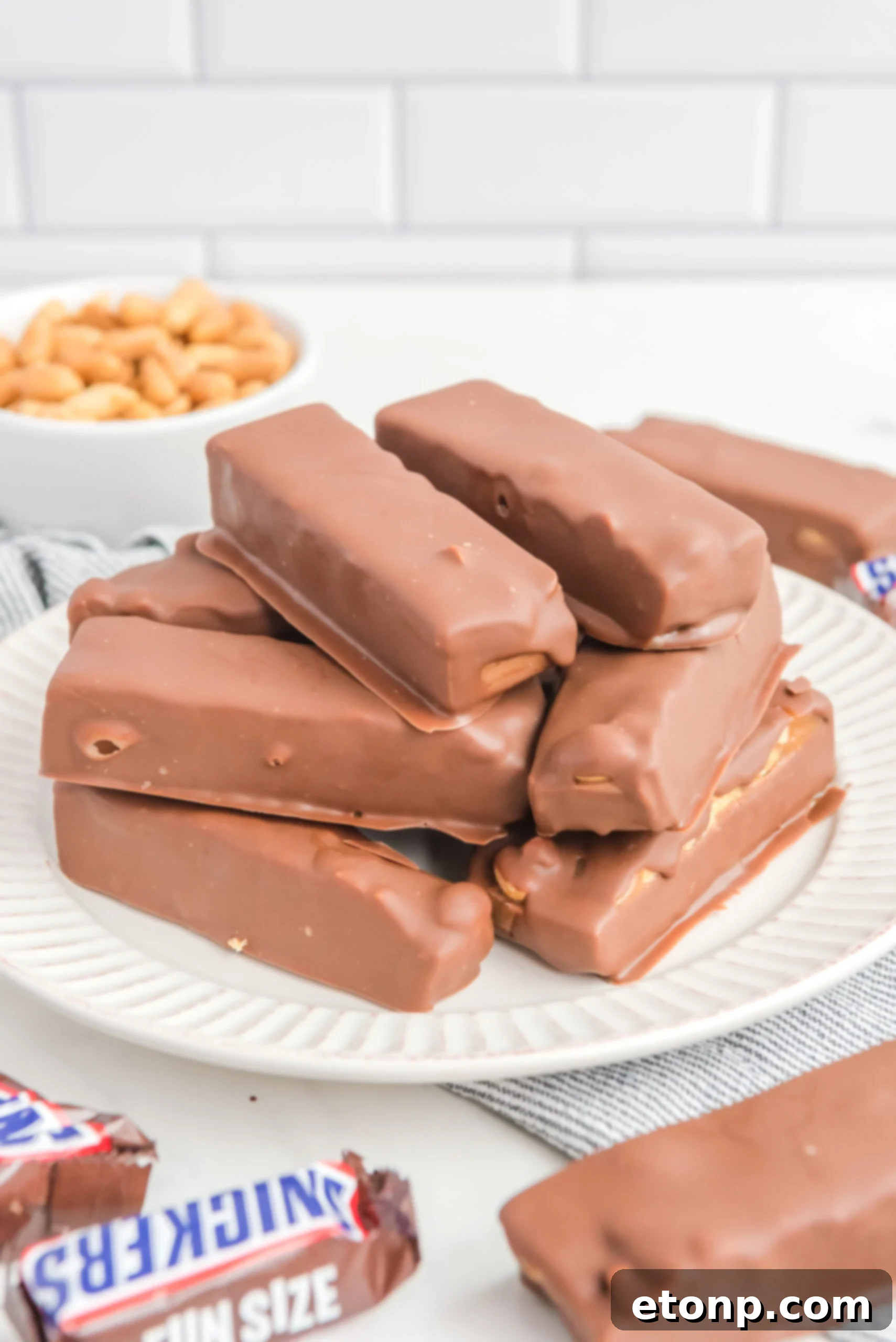 Front view of Homemade Snickers Bars stacked on a white plate.