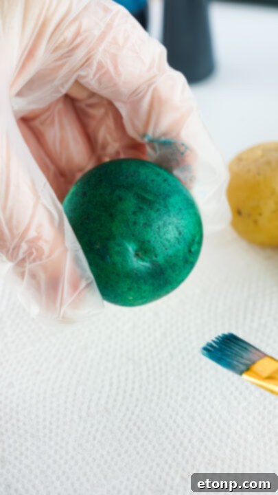 Step-by-step image showing a finished, colorful dyed potato drying on paper towels.