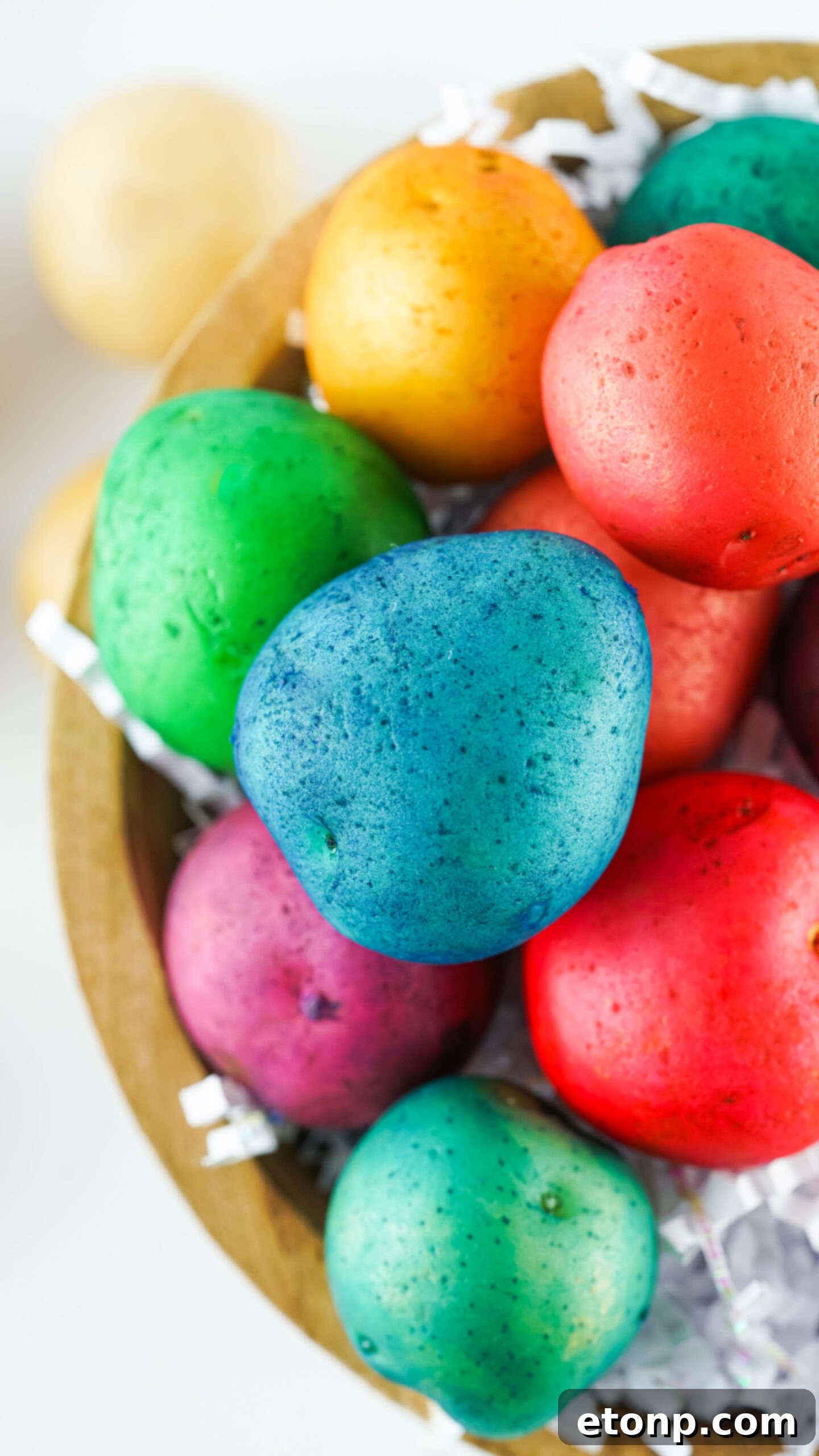 Overhead shot of an array of Dyed Easter Egg Potatoes gathered in a rustic brown bowl.