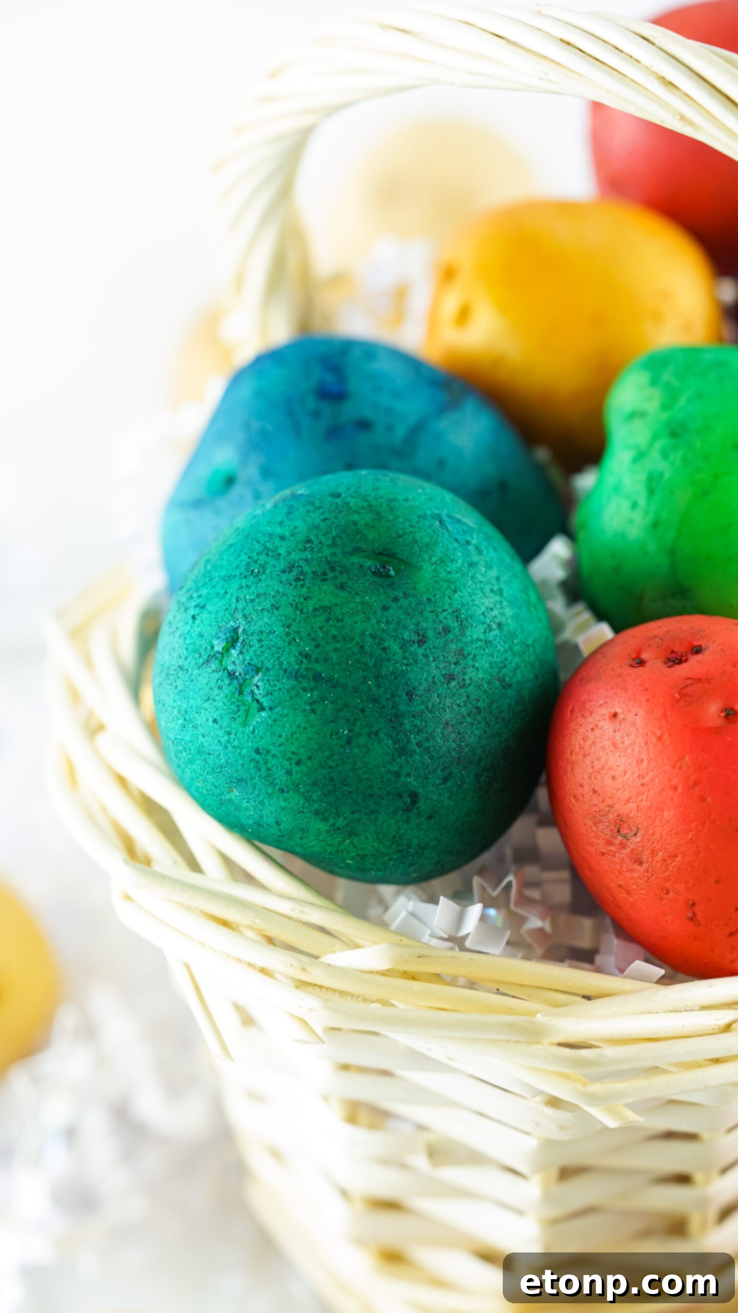 Front view of a beautiful arrangement of Dyed Easter Egg Potatoes in a rustic tan basket, ready for display.