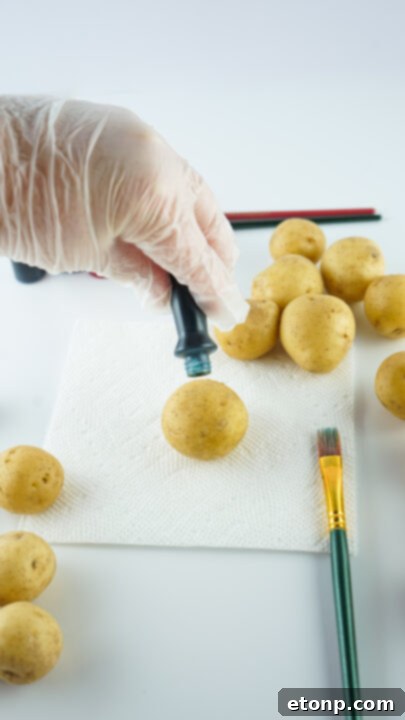 Step-by-step image of a hand applying blue dye to a potato with a paintbrush.