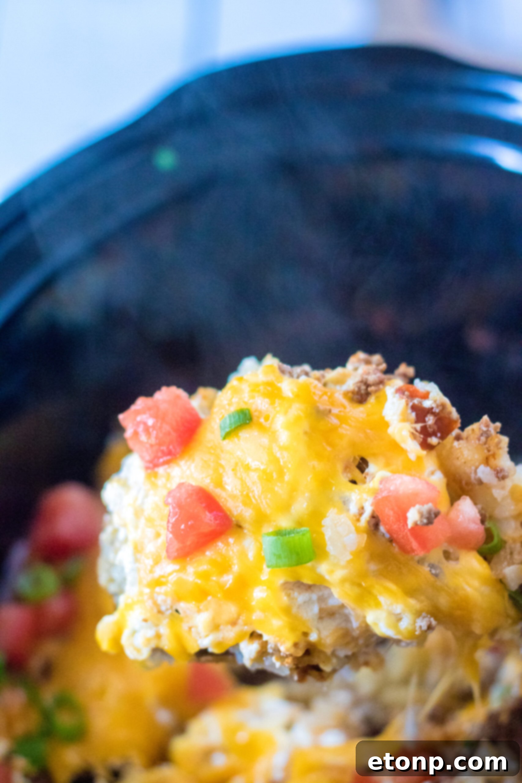 Close up view of a wooden spoon removing a serving of Slow Cooker John Wayne Casserole.