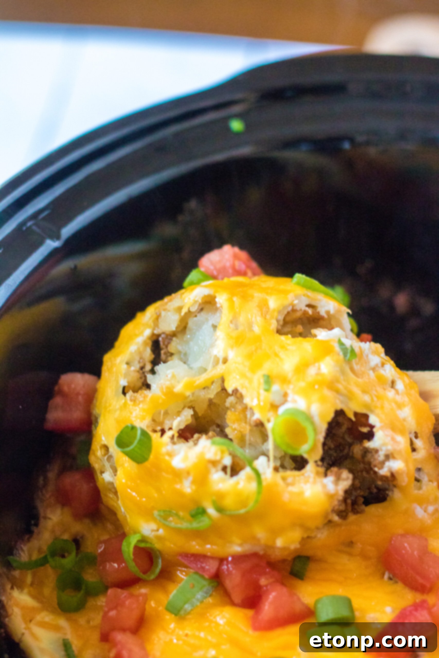 Close up view of a wooden spoon removing a serving of Slow Cooker John Wayne Casserole.