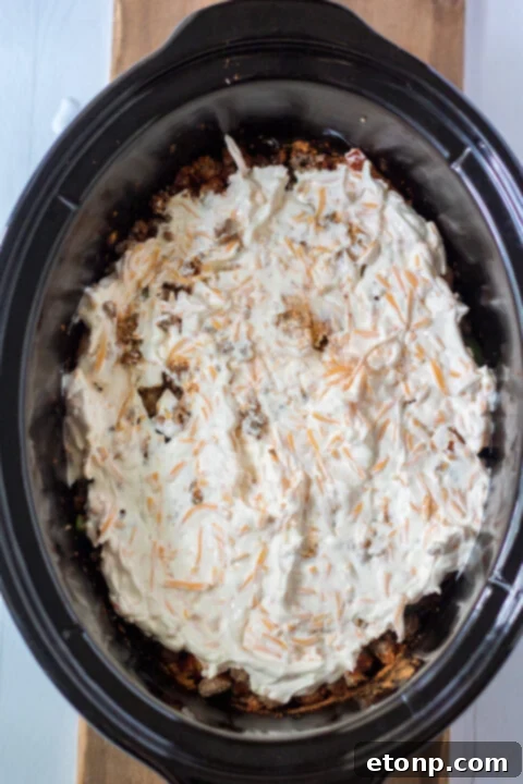 Layering ingredients in a slow cooker for John Wayne Casserole.