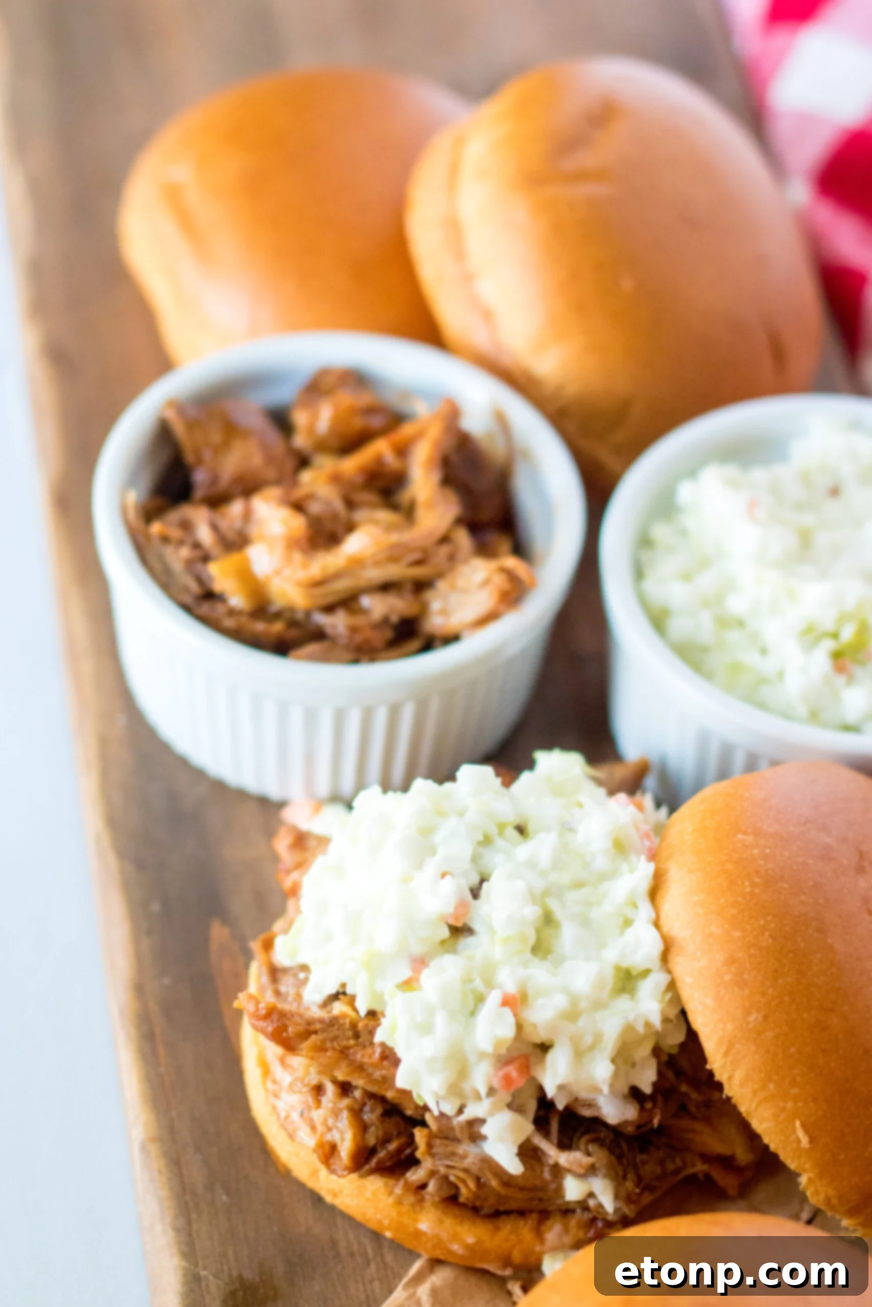 Close up view of Slow Cooker Cola Pulled Pork on a bun served with coleslaw.