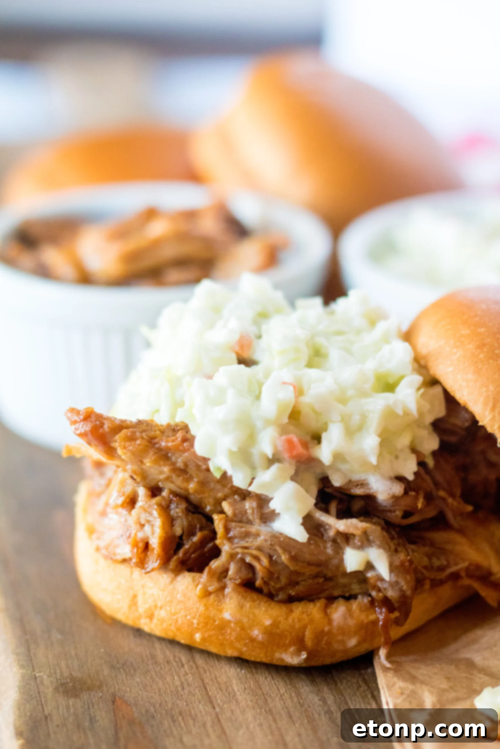 Close up view of Slow Cooker Cola Pulled Pork on a bun served with coleslaw.