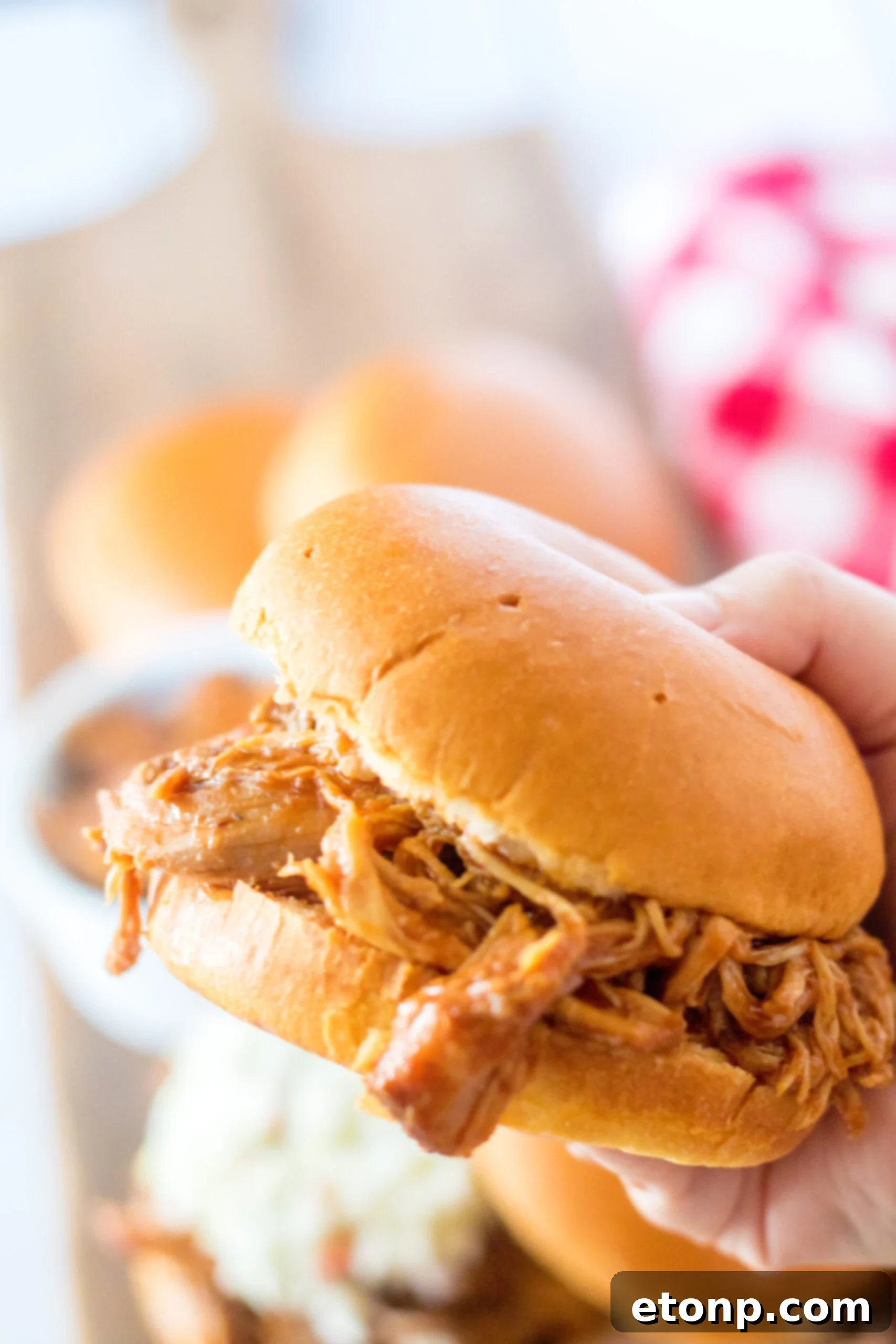 Front view of a Slow Cooker Cola Pulled pork sandwich being held.