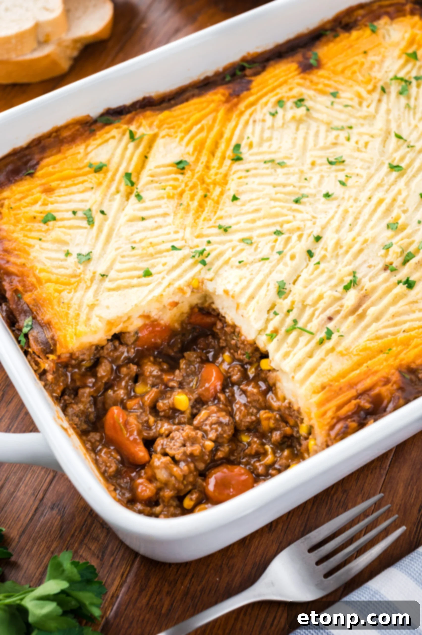 A shot of the Shepherd's pie in a white baking dish with a piece removed showing the filling. 